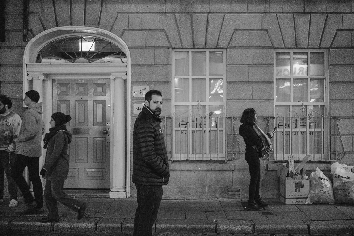 People gathering outside a historic Georgian building entrance at night.