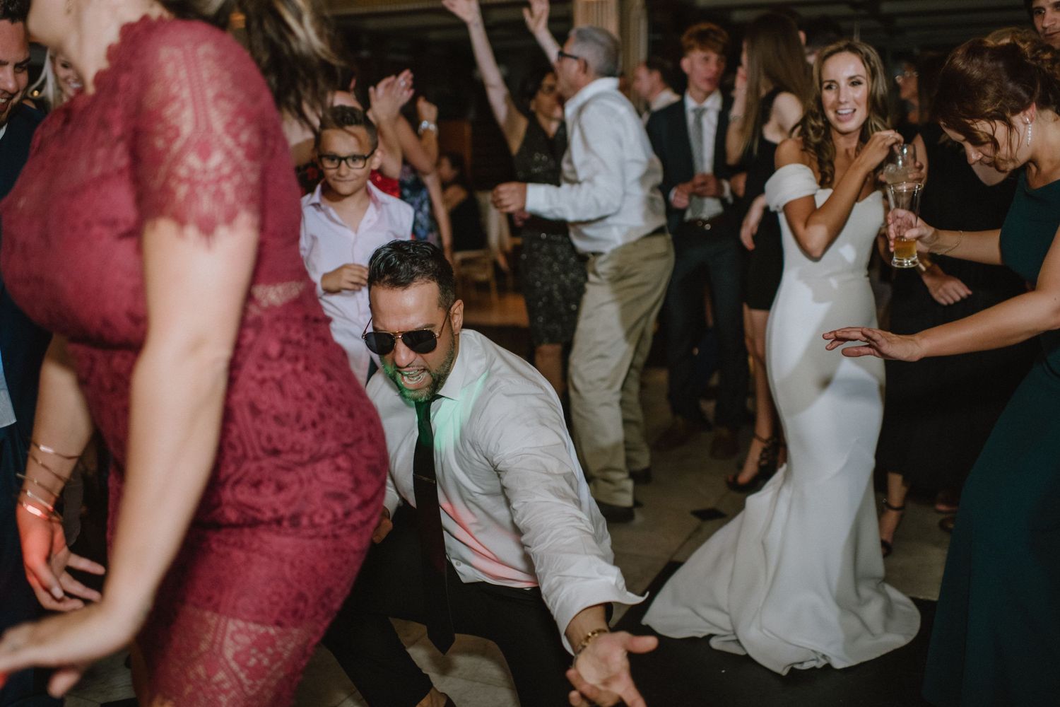 Wedding guests dance energetically during a lively reception party.