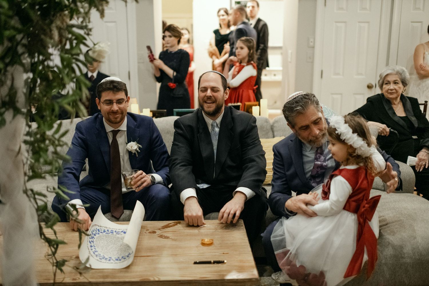 A group of guests in formal attire gather around a table during a celebration.