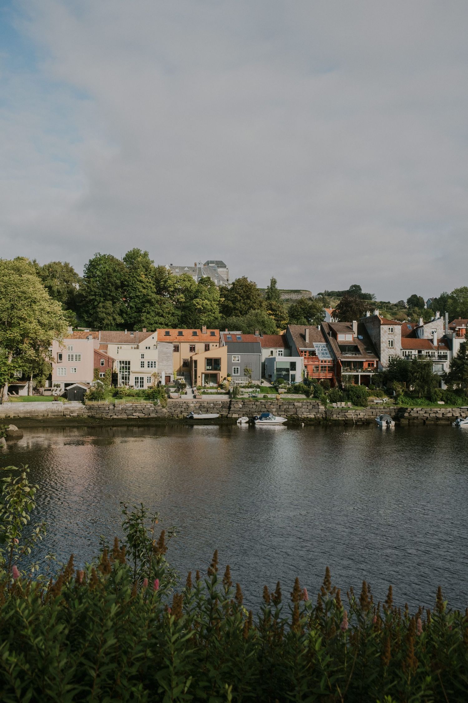 Colorful waterfront homes line a peaceful harbor with boats and lush greenery.