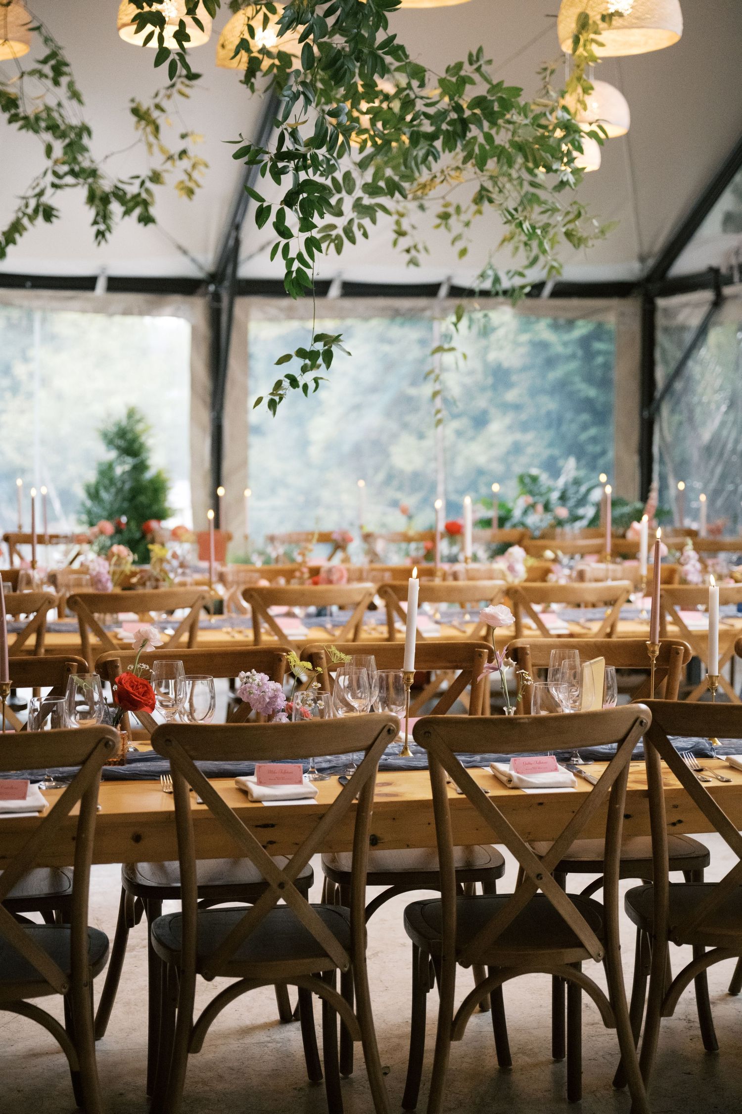A rustic wedding reception venue with wooden chairs and hanging greenery decorations.