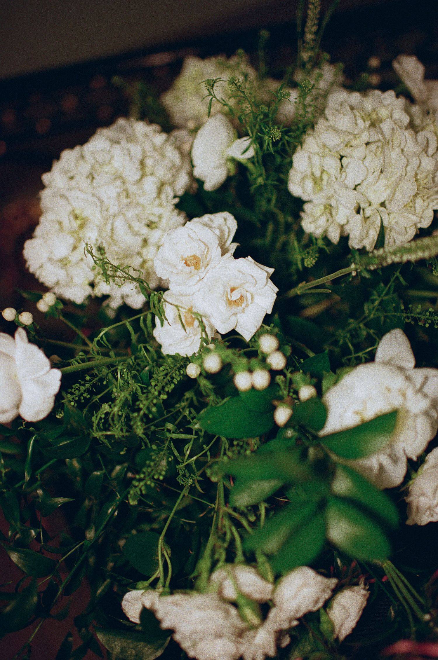 Close-up of white roses and hydrangeas in elegant wedding floral arrangement.