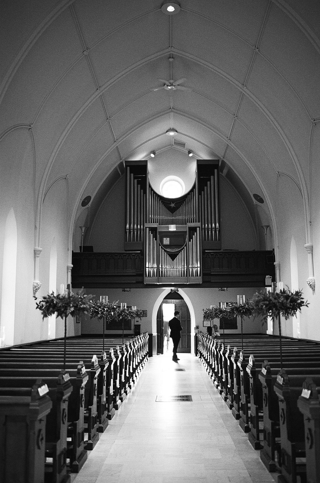 Interior view of a traditional church with wooden pews and pipe organ leading to a bright altar.