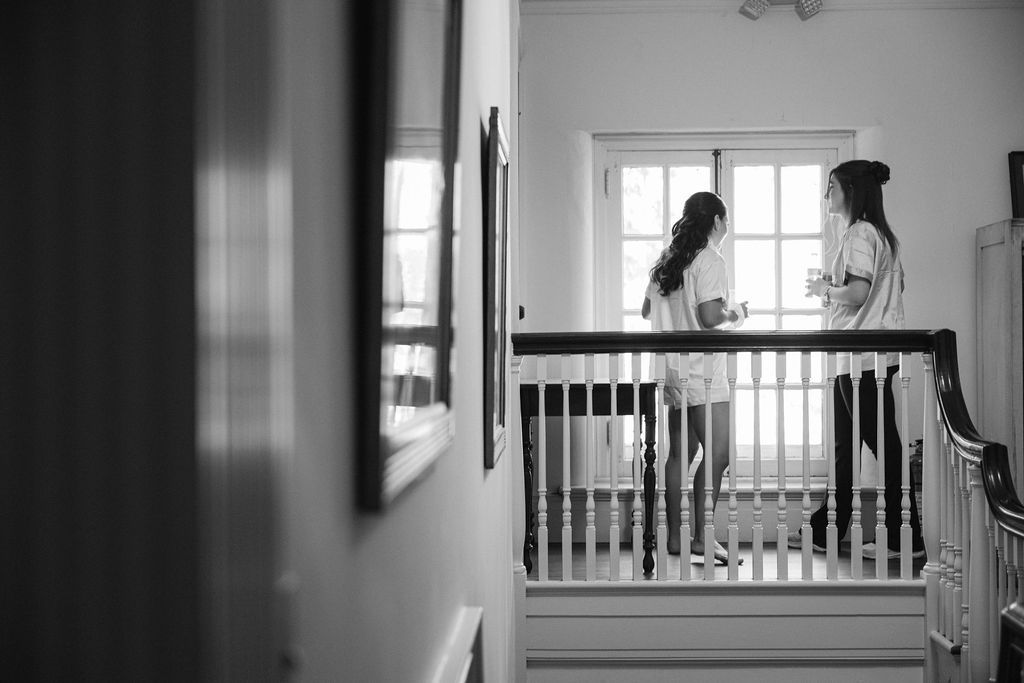 Black and white image of a hallway interior with figures silhouetted against natural light.