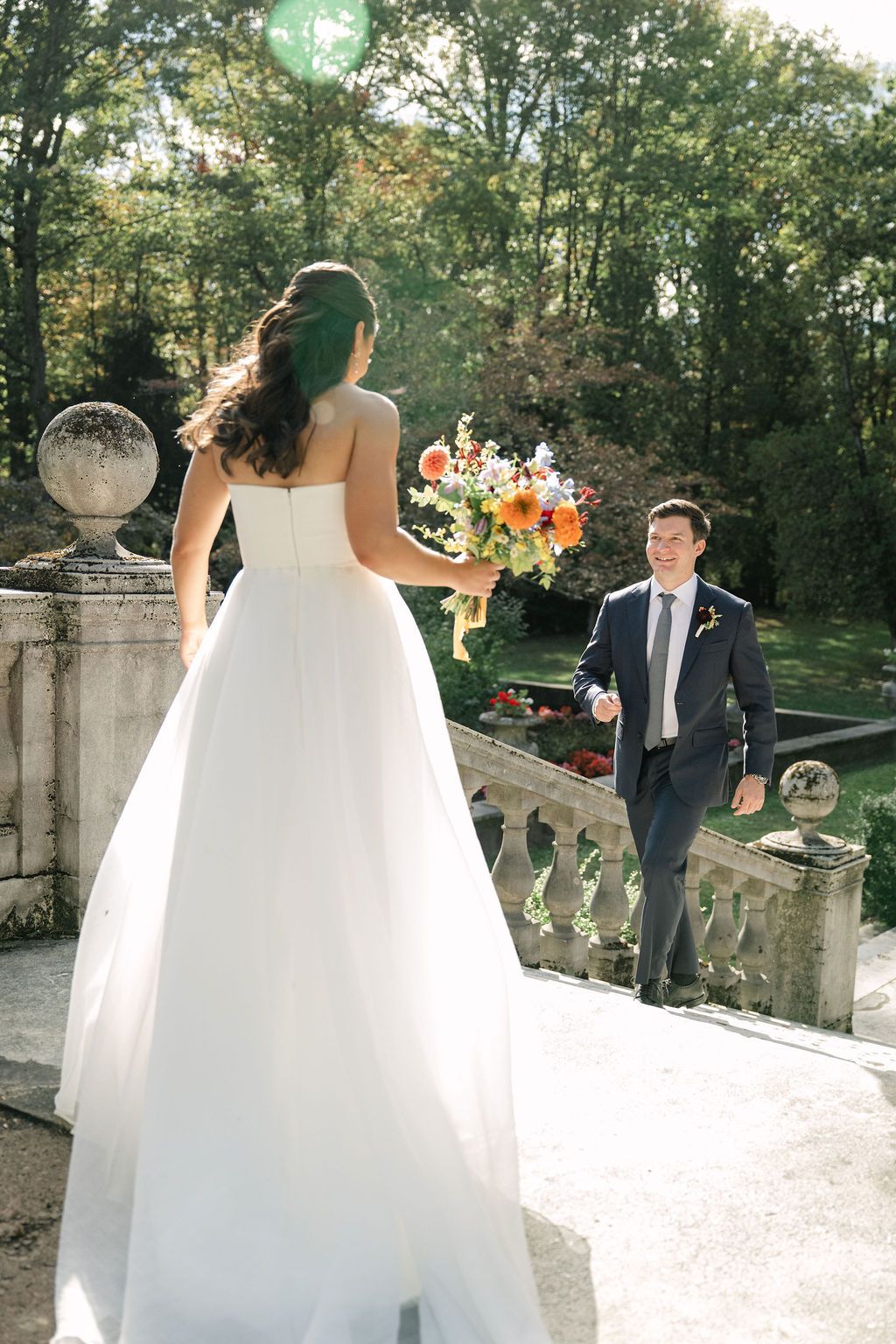 A bride in a flowing white gown poses on an elegant stone terrace.
