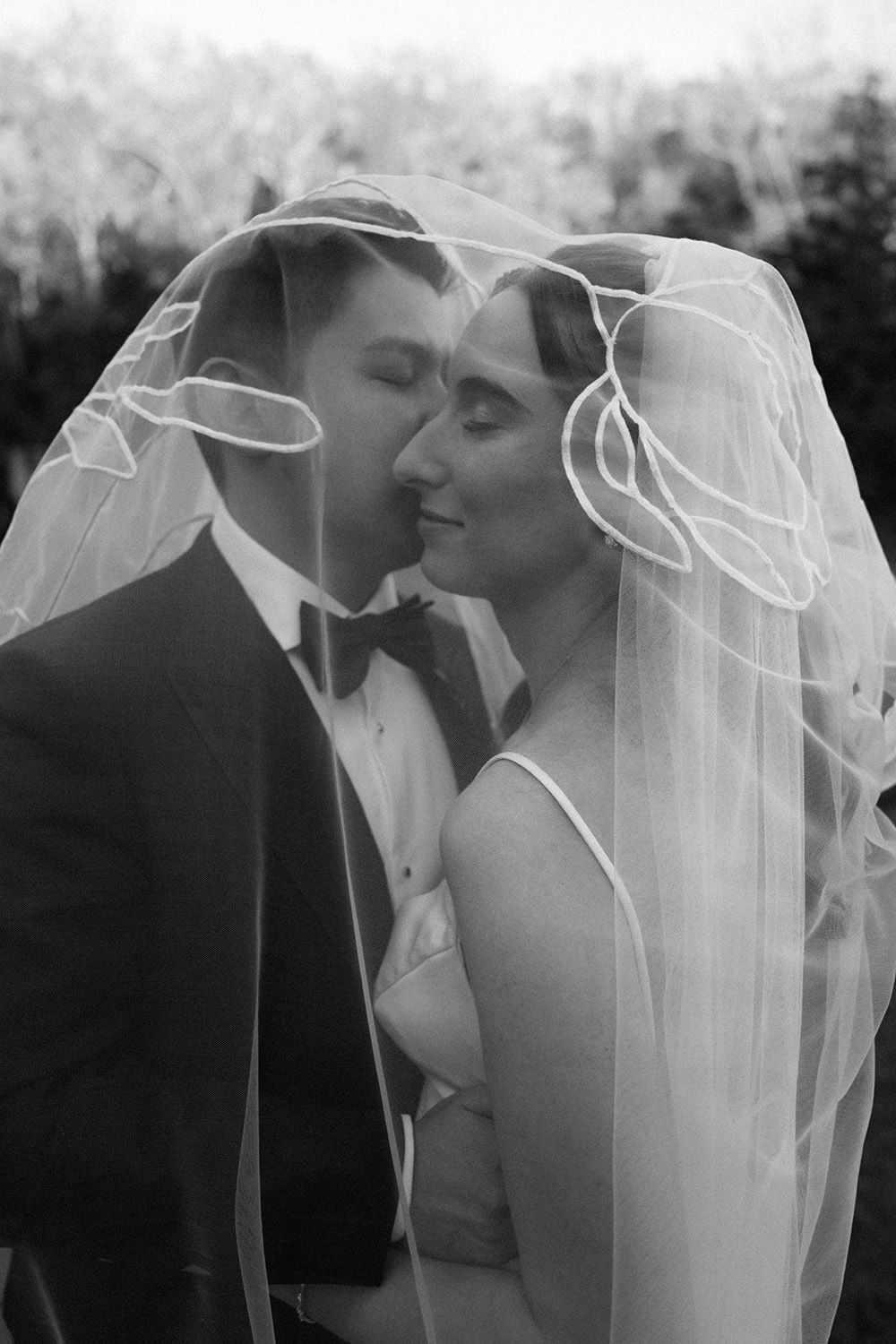 Black and white wedding photos showing intimate romantic moments between newlyweds under a flowing veil.