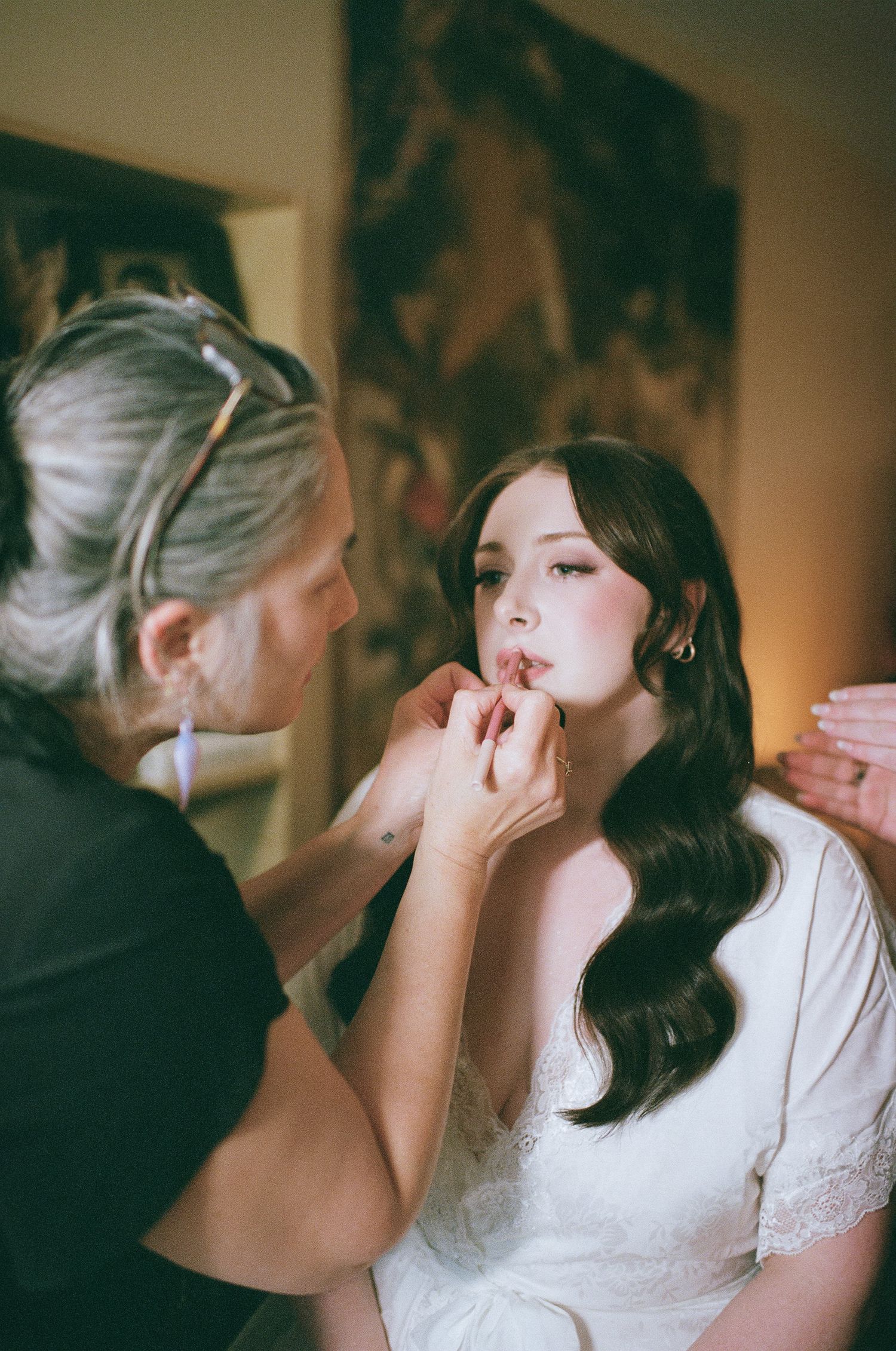 Makeup being applied during wedding preparation.