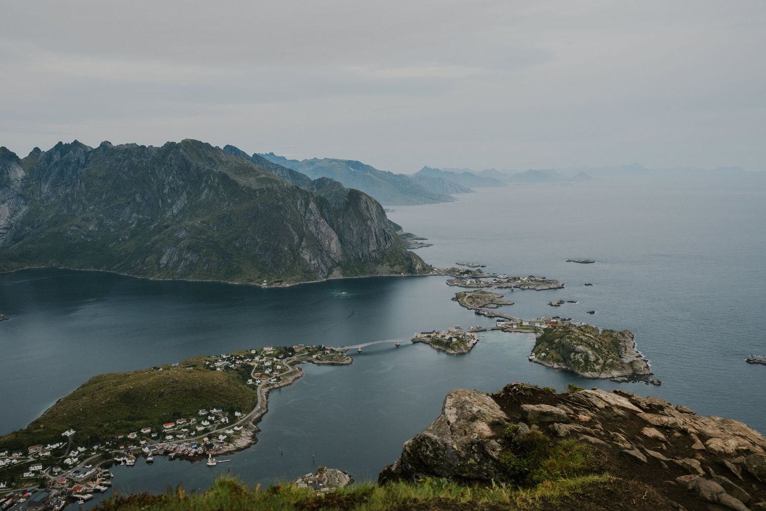 Aerial view of a coastal village nestled between mountains and fjords in Norway.