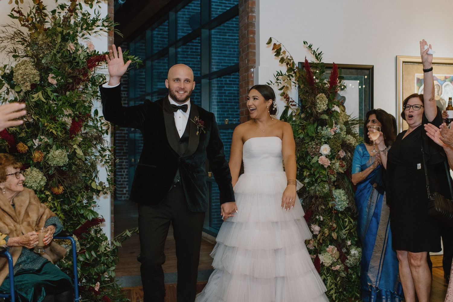 A wedding celebration moment with floral arch decor and decorative greenery.