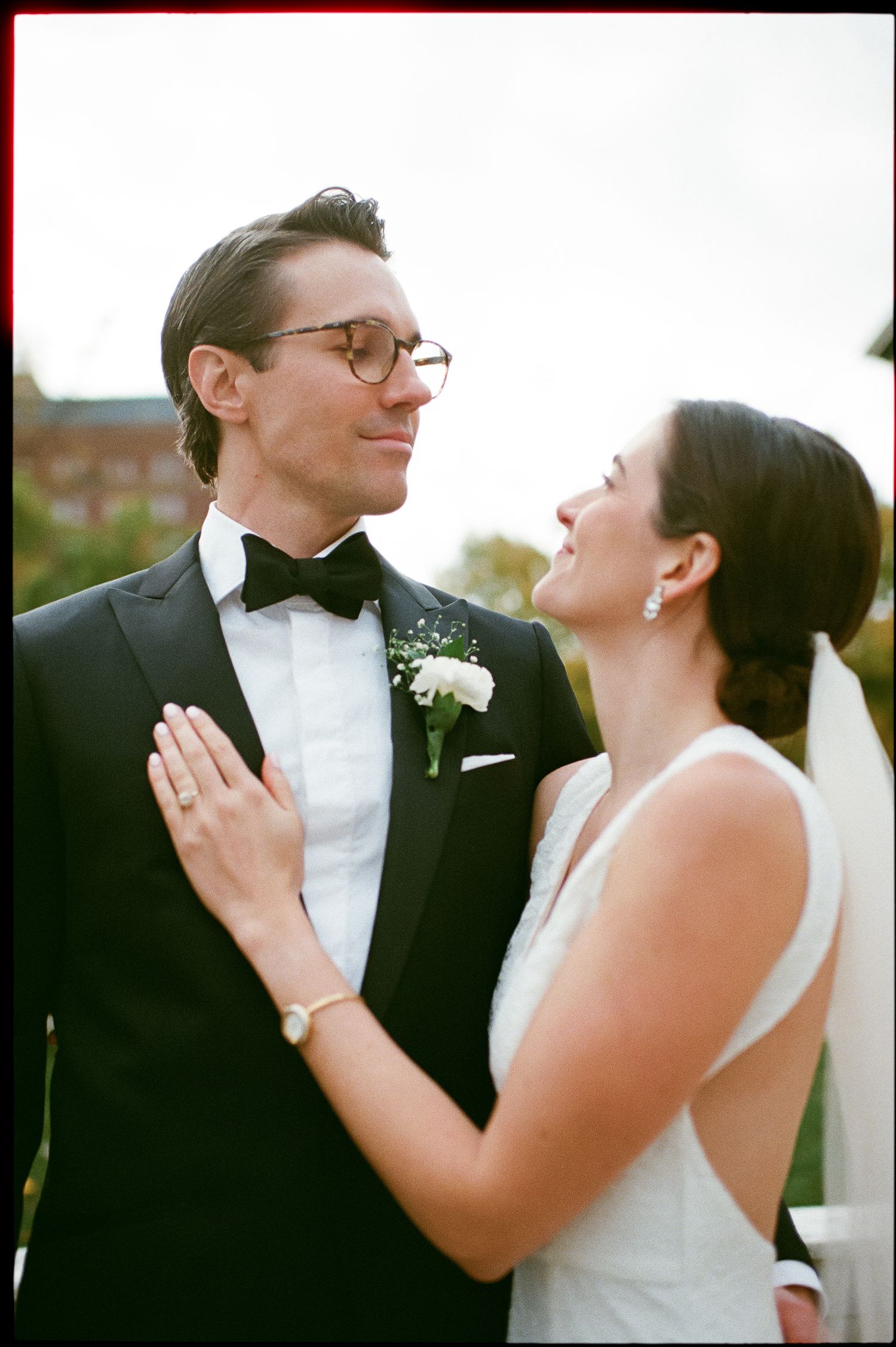 A tender wedding moment between newlyweds sharing laughter outdoors.