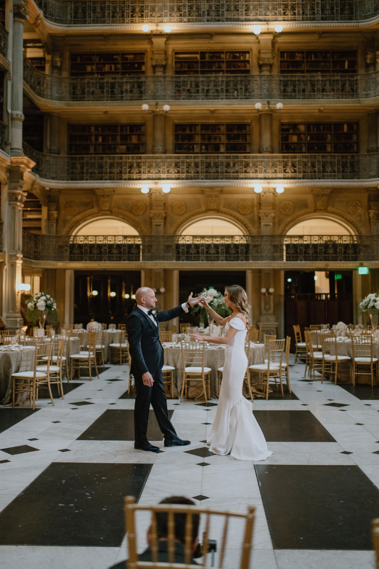 Elegant wedding reception in a historic library with multiple floors and ornate architecture.