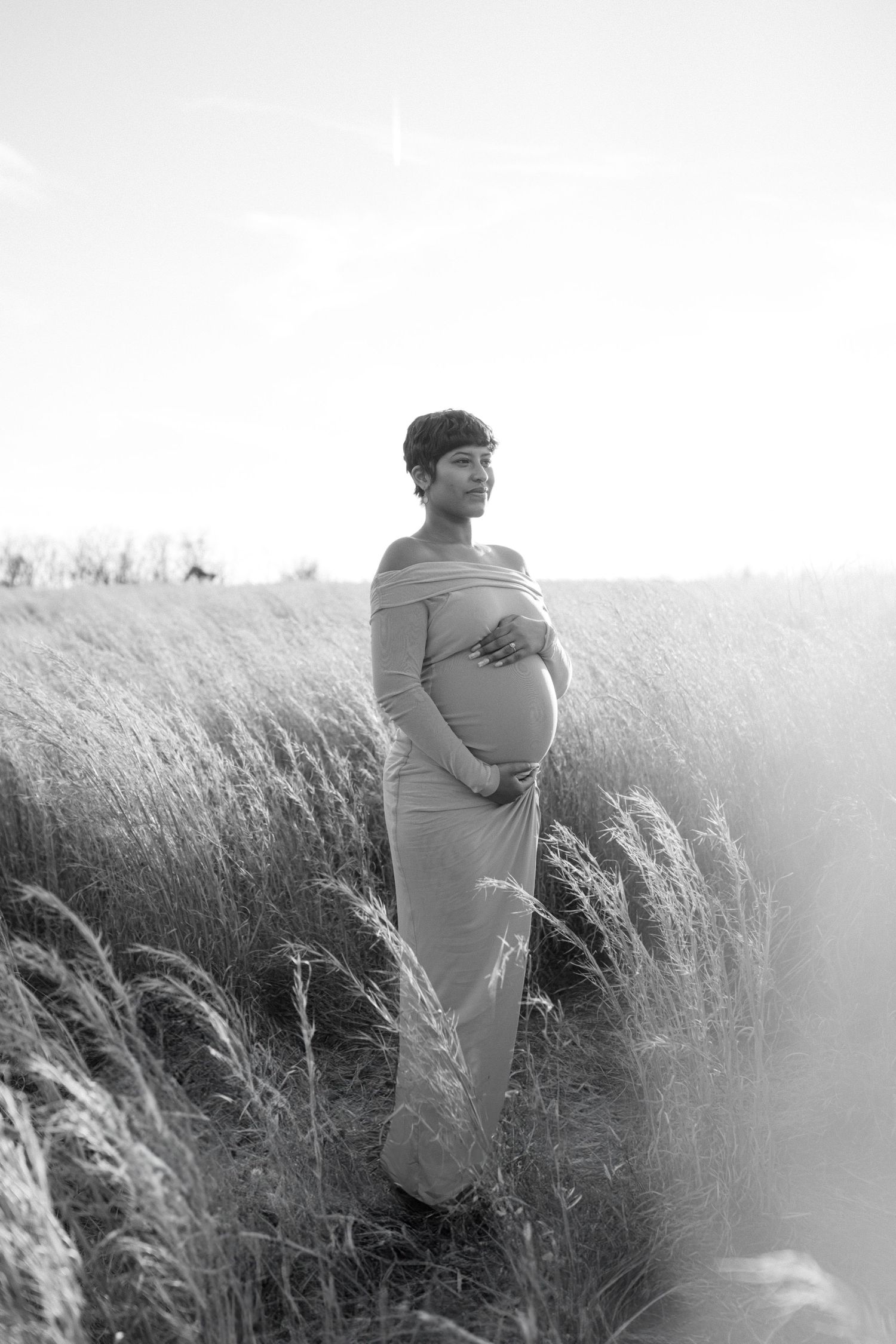 maternity photo of woman holding baby bump in field