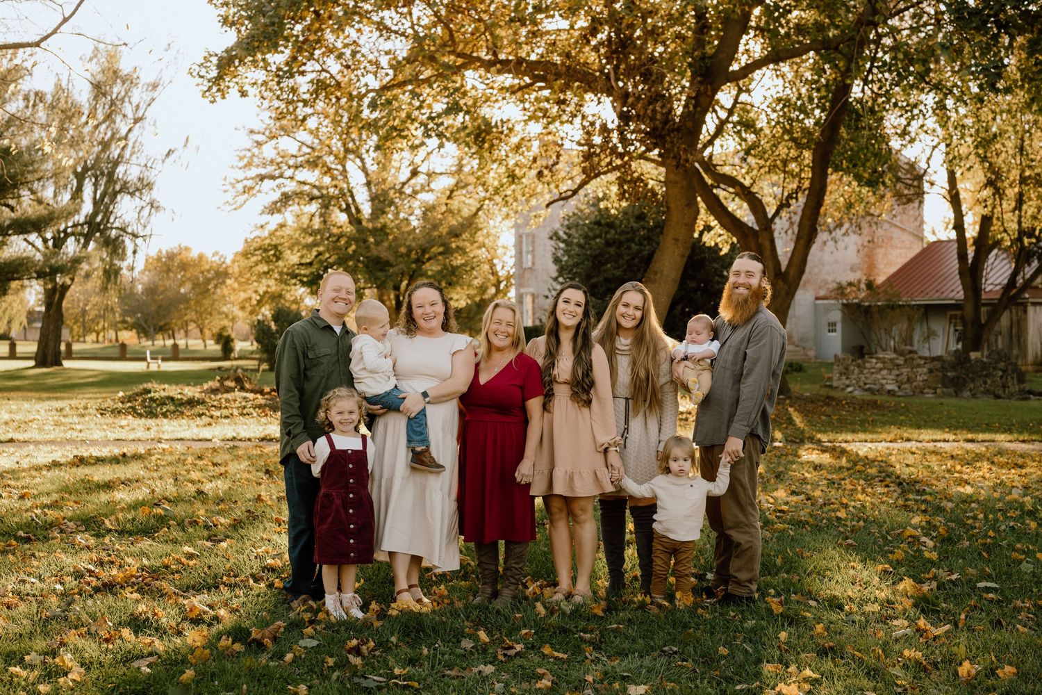 Group portrait of family members standing together on fallen autumn leaves.