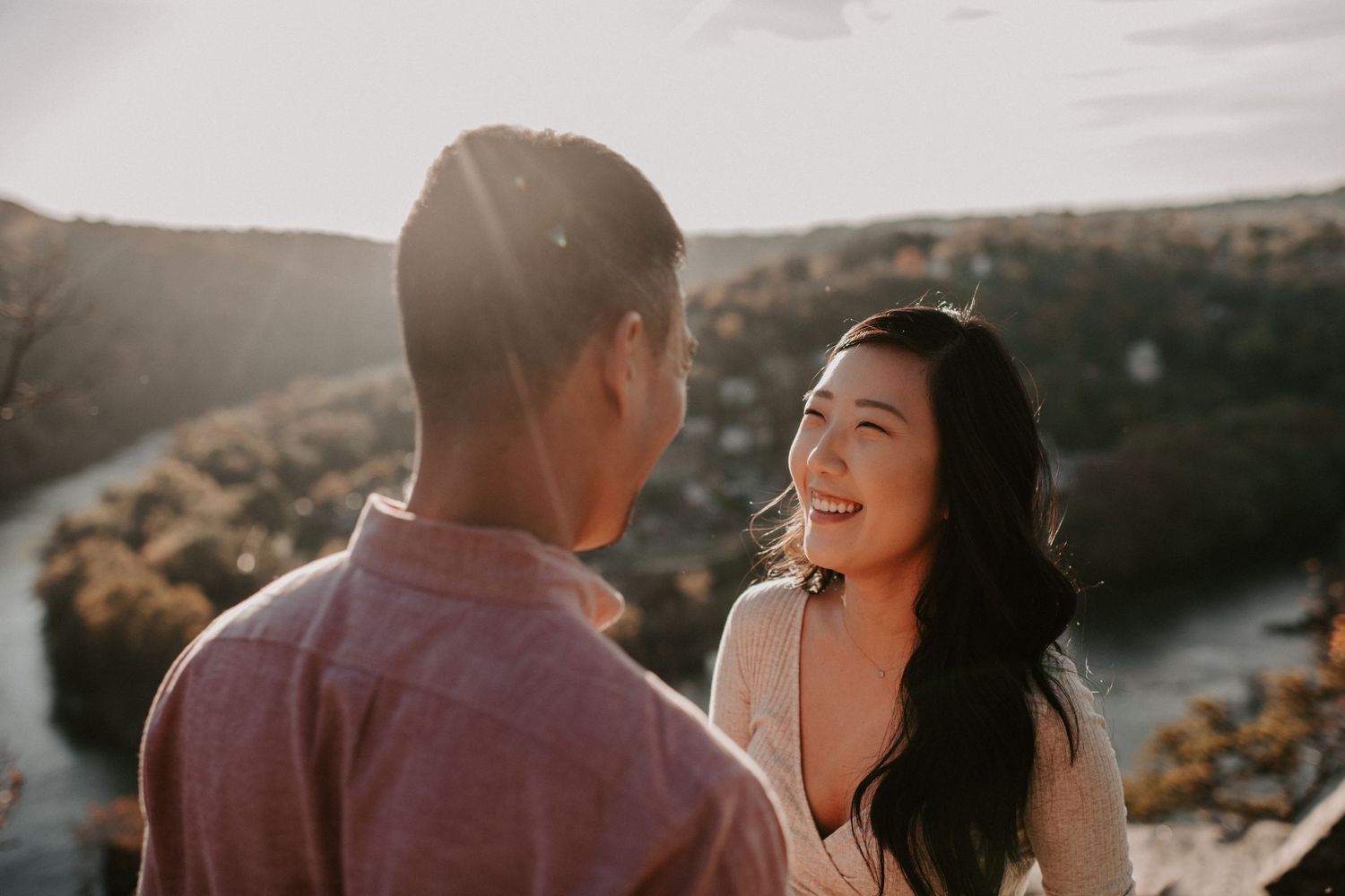 A couple sharing a joyful moment at sunset on a scenic overlook.
