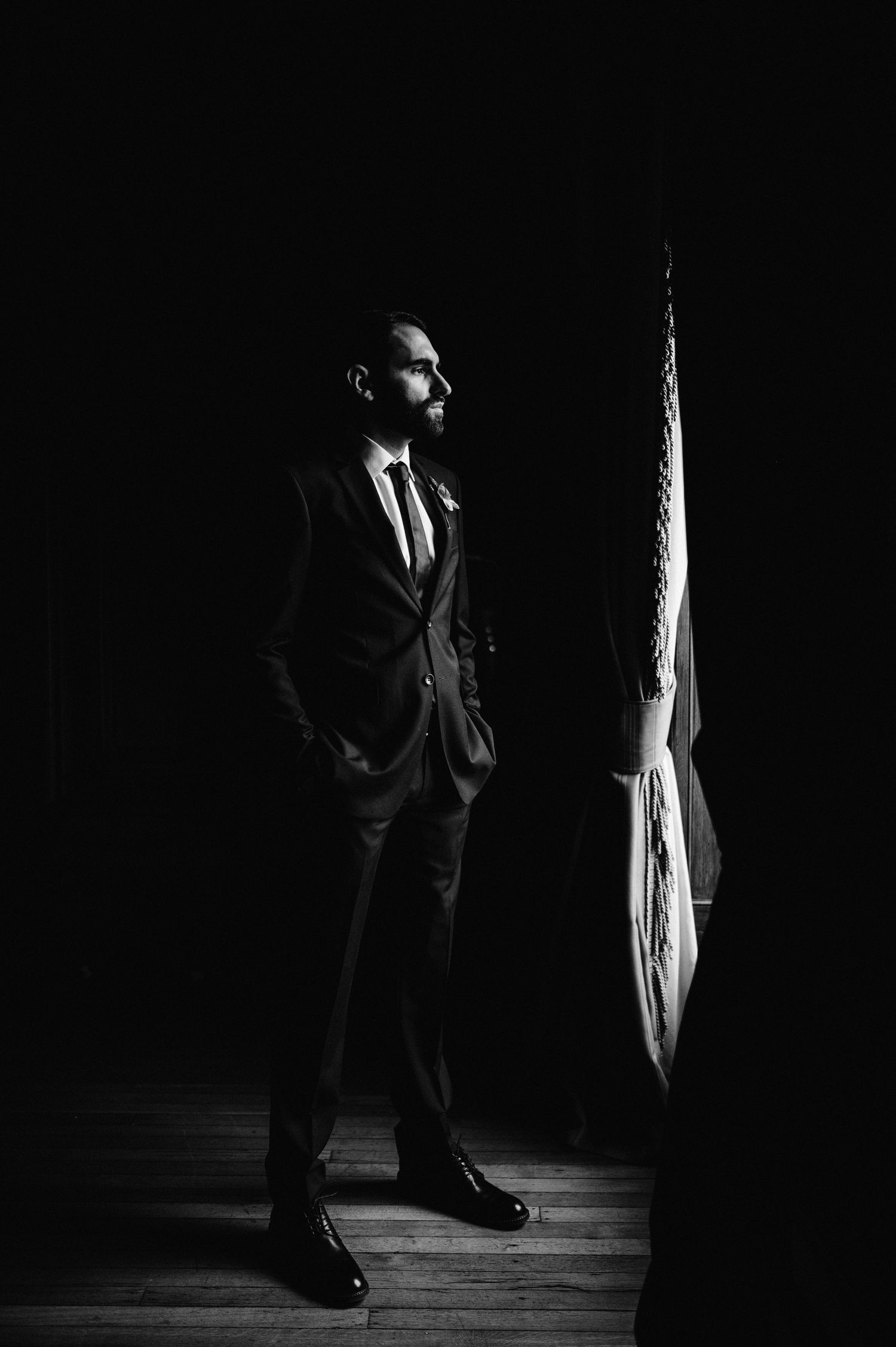 Silhouetted figure in a suit standing against dark background with dramatic side lighting.