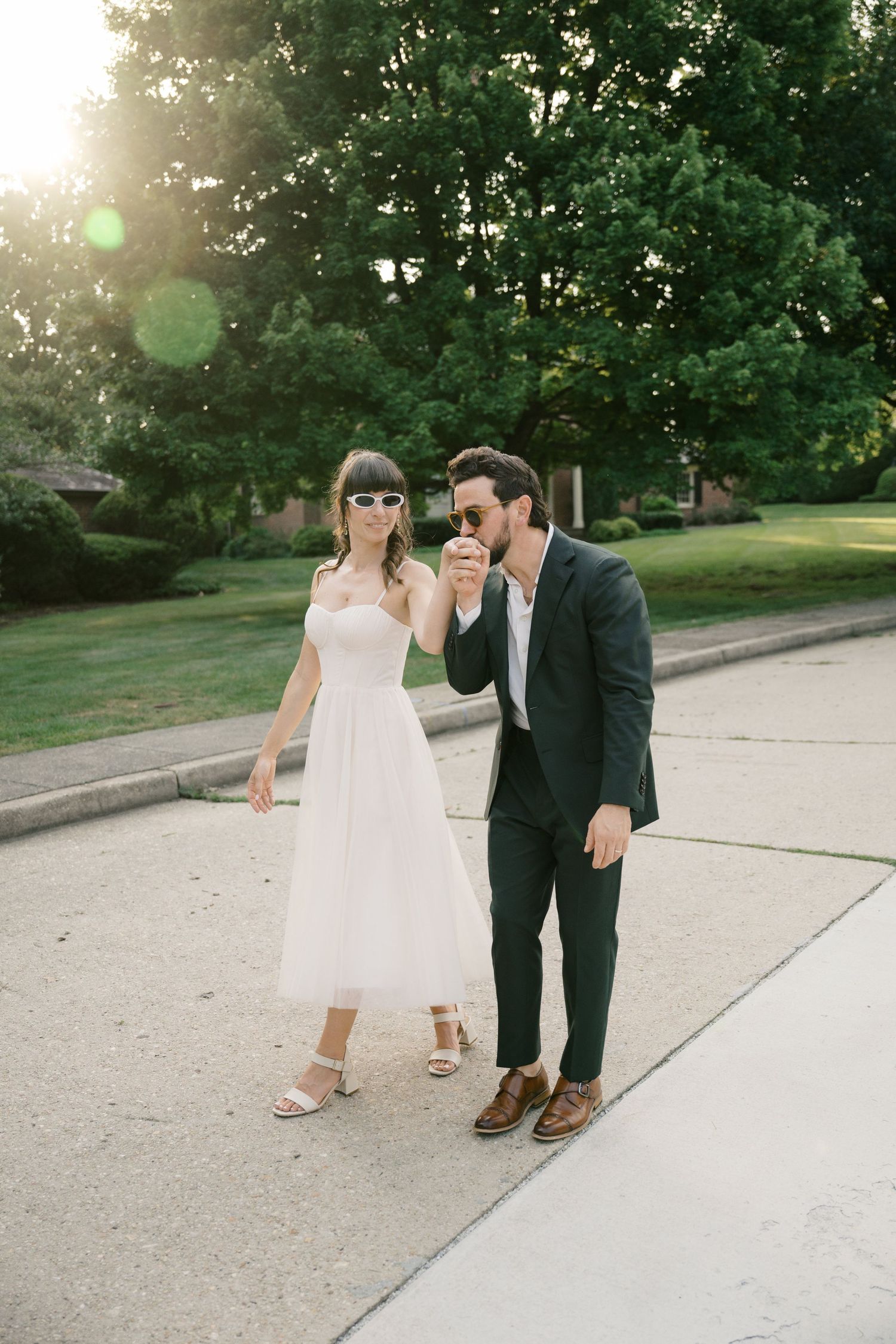 Sunlit pathway scene with couple in wedding attire walking together on a summer evening.