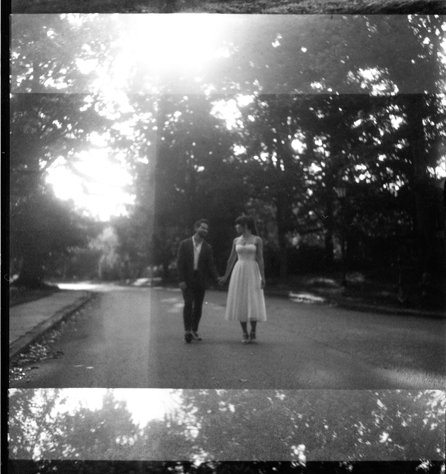 Black and white panoramic park scene with figures walking on path.