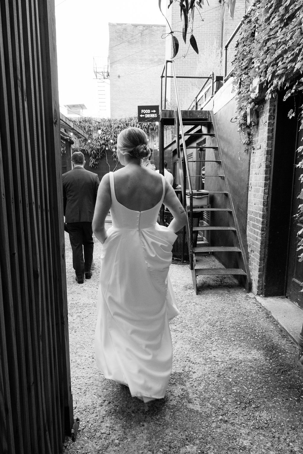 Wedding couple walks through an industrial alleyway with metal gates.