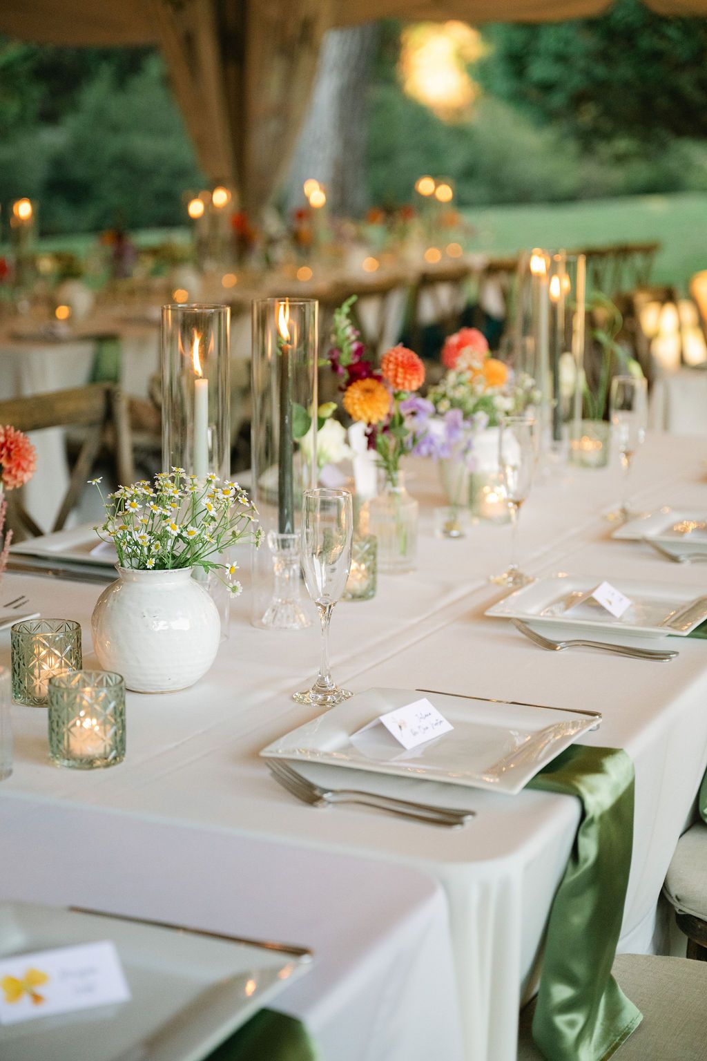 Elegant wedding reception table settings with white linens, candles and delicate floral centerpieces.