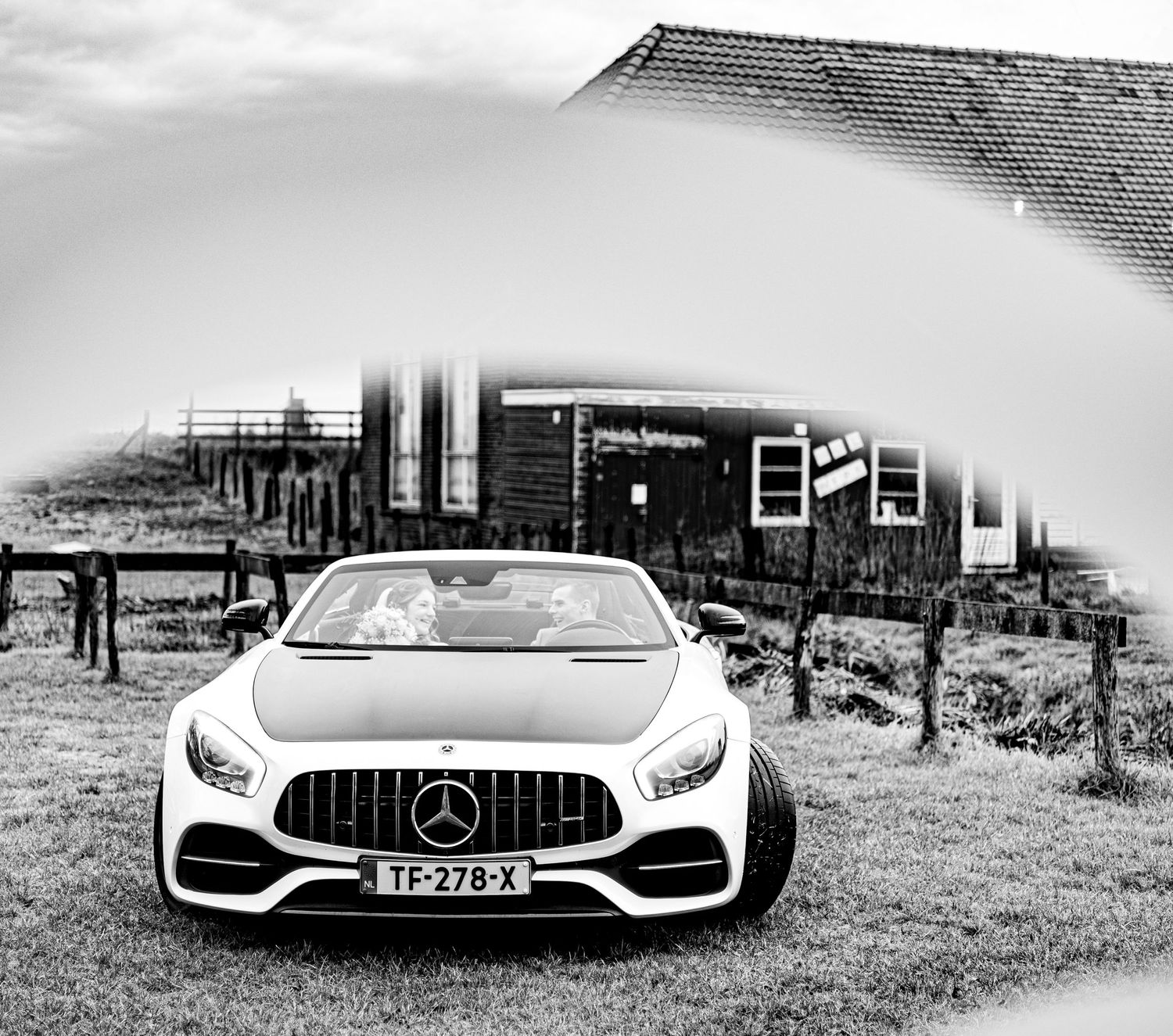 Sleek white Mercedes AMG GT convertible parked against a dramatic black and white landscape. Trouwauto. Trouwfoto.