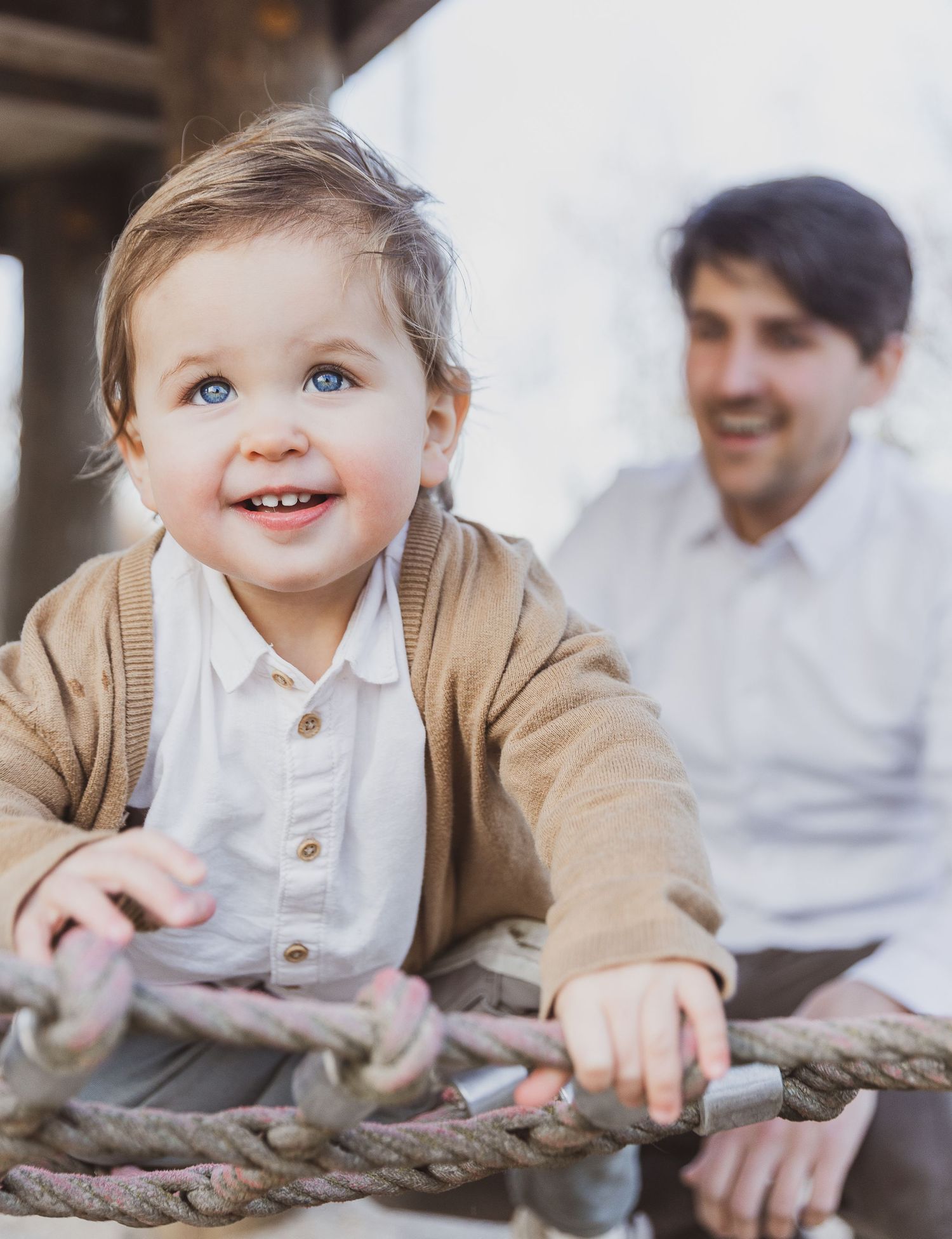 A joyful moment captured between a toddler and parent on a rustic wooden structure. Gezinsfoto Nederland. Relaxte sfeer.