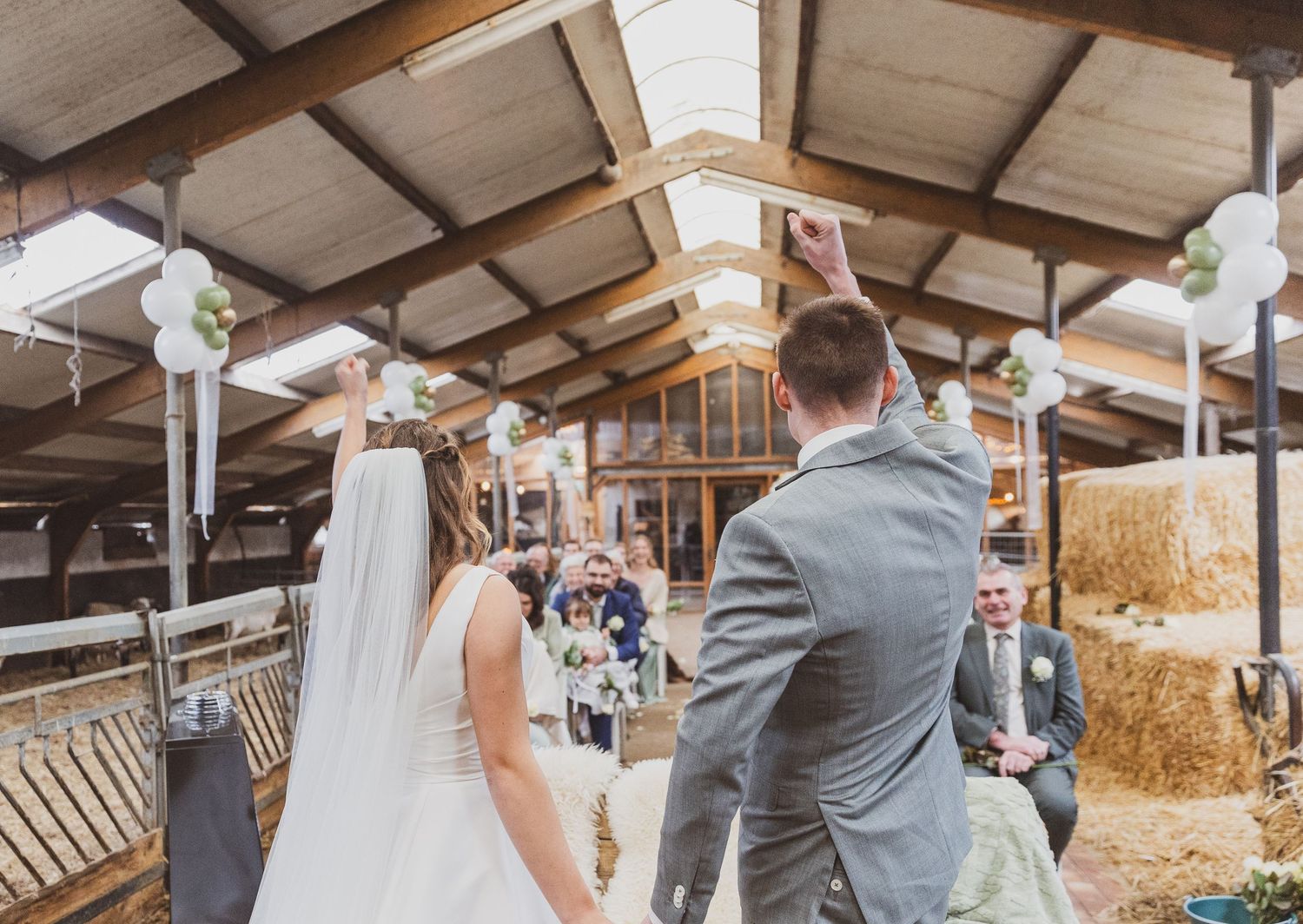 Wedding ceremony setup in rustic barn venue with hay bales and white decorations. Trouwfotograaf Nederland