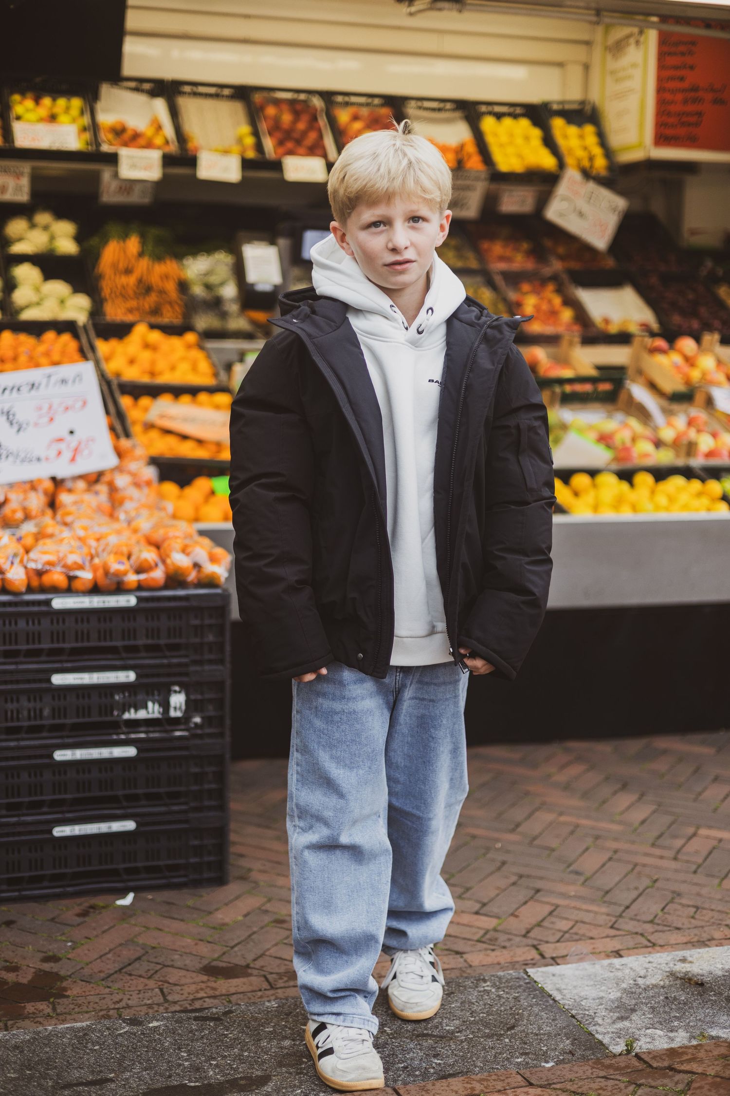 A series of photos showing someone in jeans and white sneakers standing near produce displays at a market.