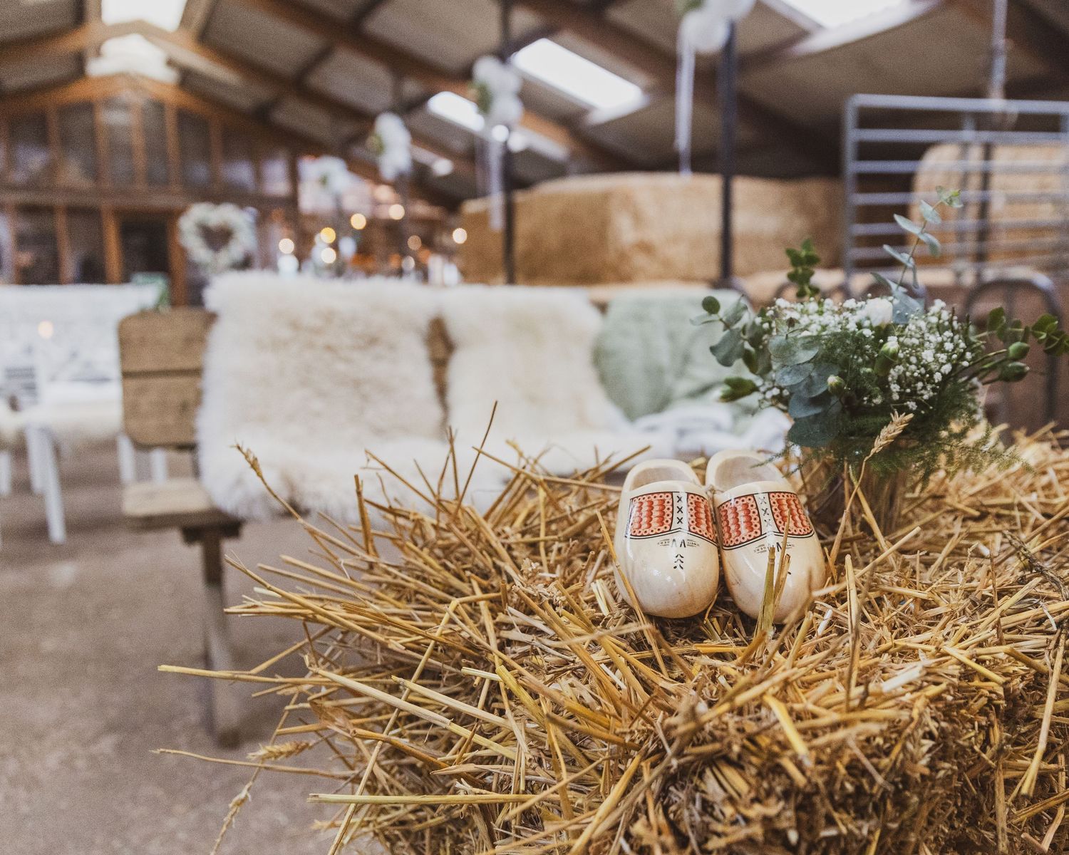 Wedding shoes displayed on hay bales with rustic barn reception decor. Wedding photographer Netherlands.