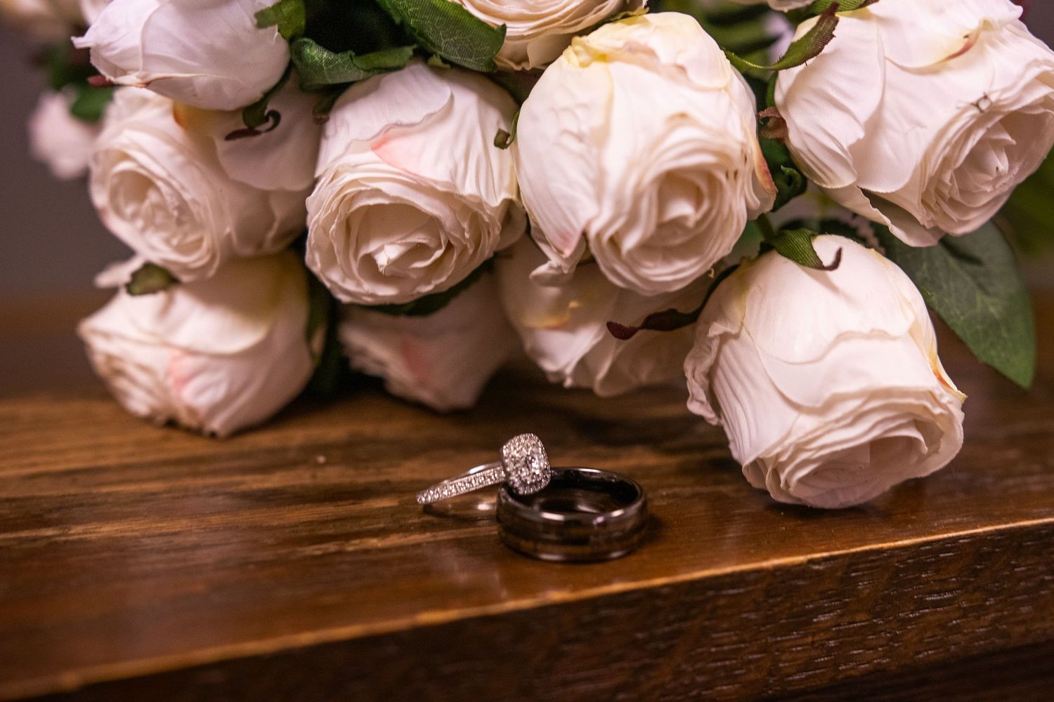 A row of delicate pink roses arranged on a rustic wooden surface with soft lighting and natural shadows.