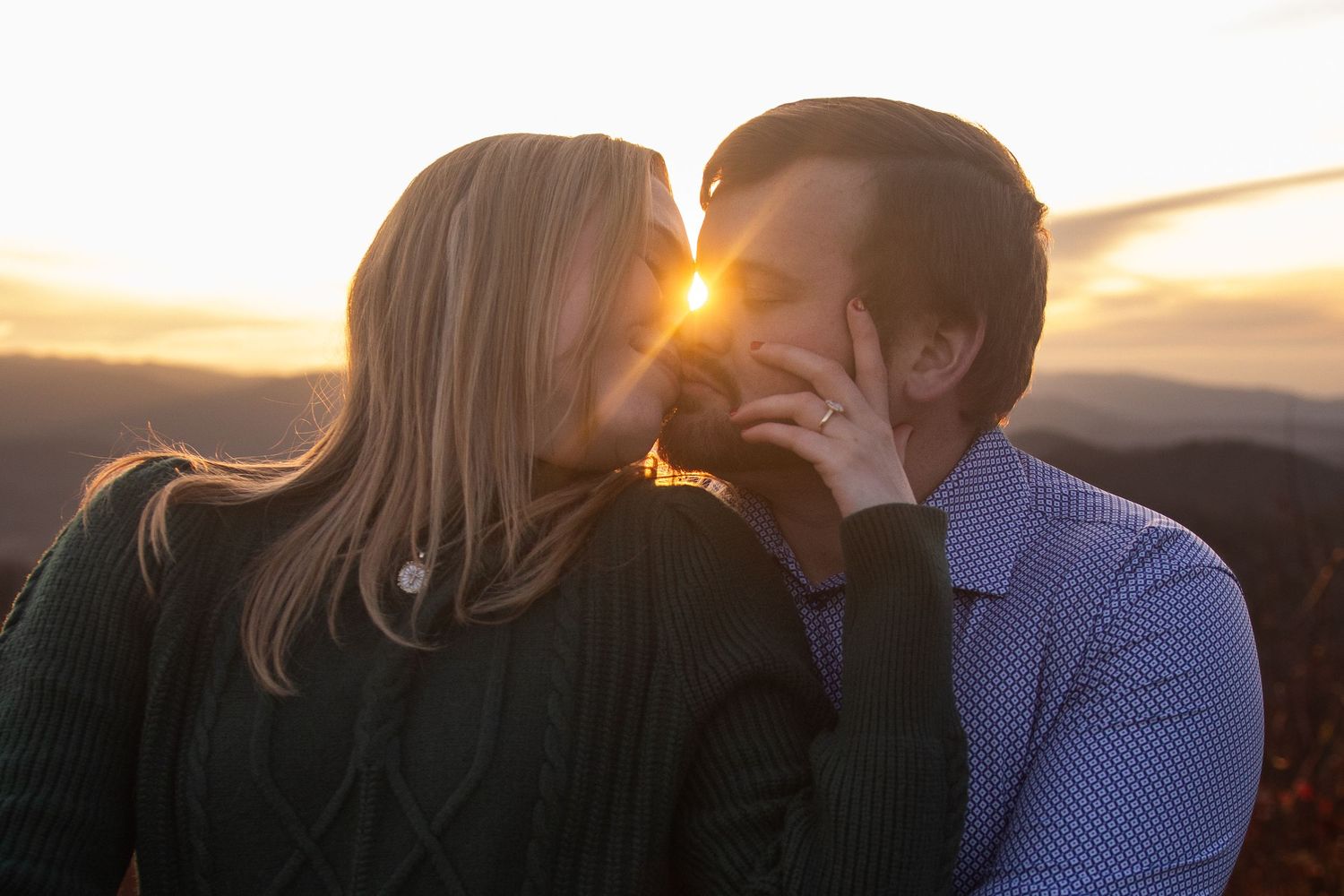A couple shares a romantic kiss during a beautiful golden sunset by the ocean.