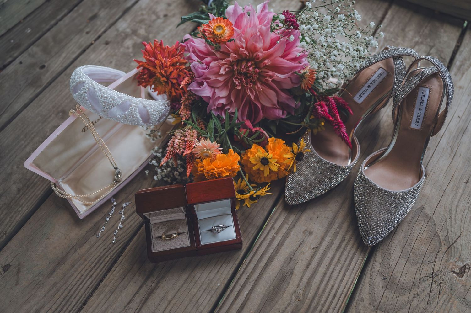A collection of colorful dahlias and autumn flowers arranged with vintage items on rustic wooden planks.