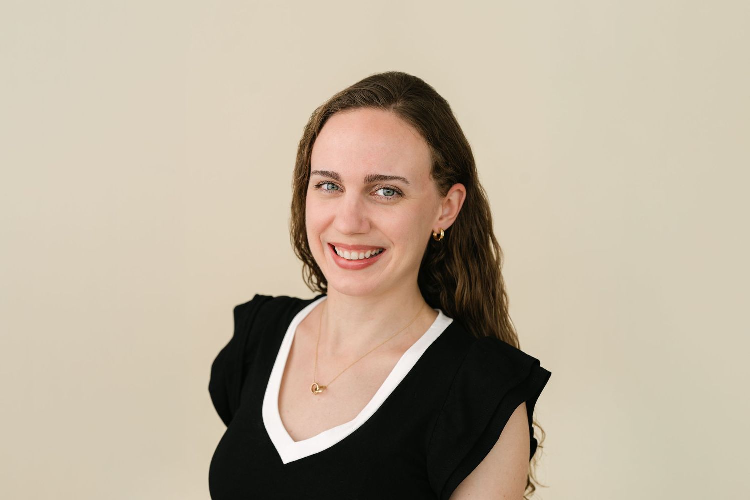 Professional headshot photo featuring someone in a black blazer and white collared shirt against a neutral background.