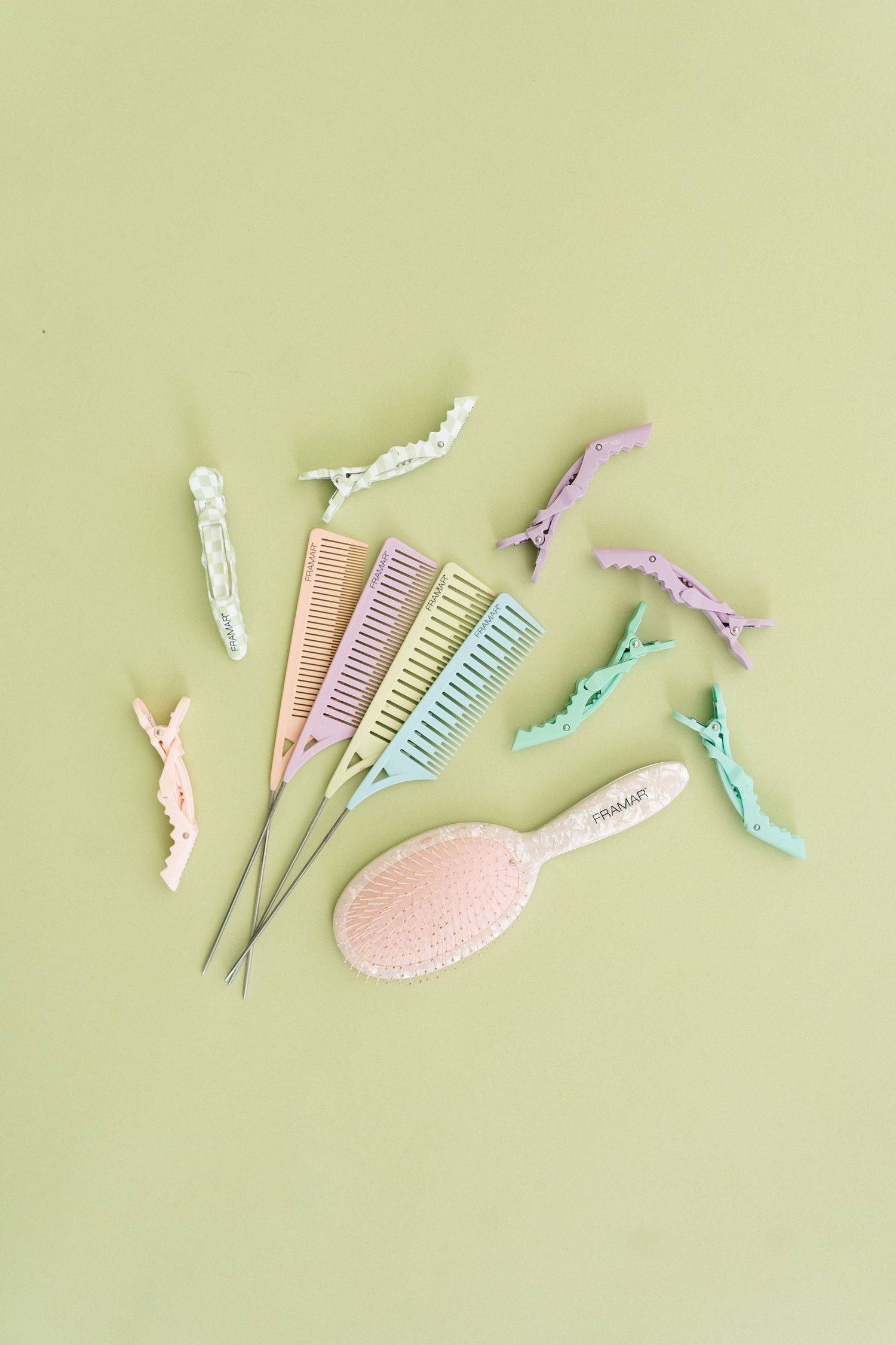 Pastel hair accessories including combs and hair clips arranged on a light green background in a minimalist style.