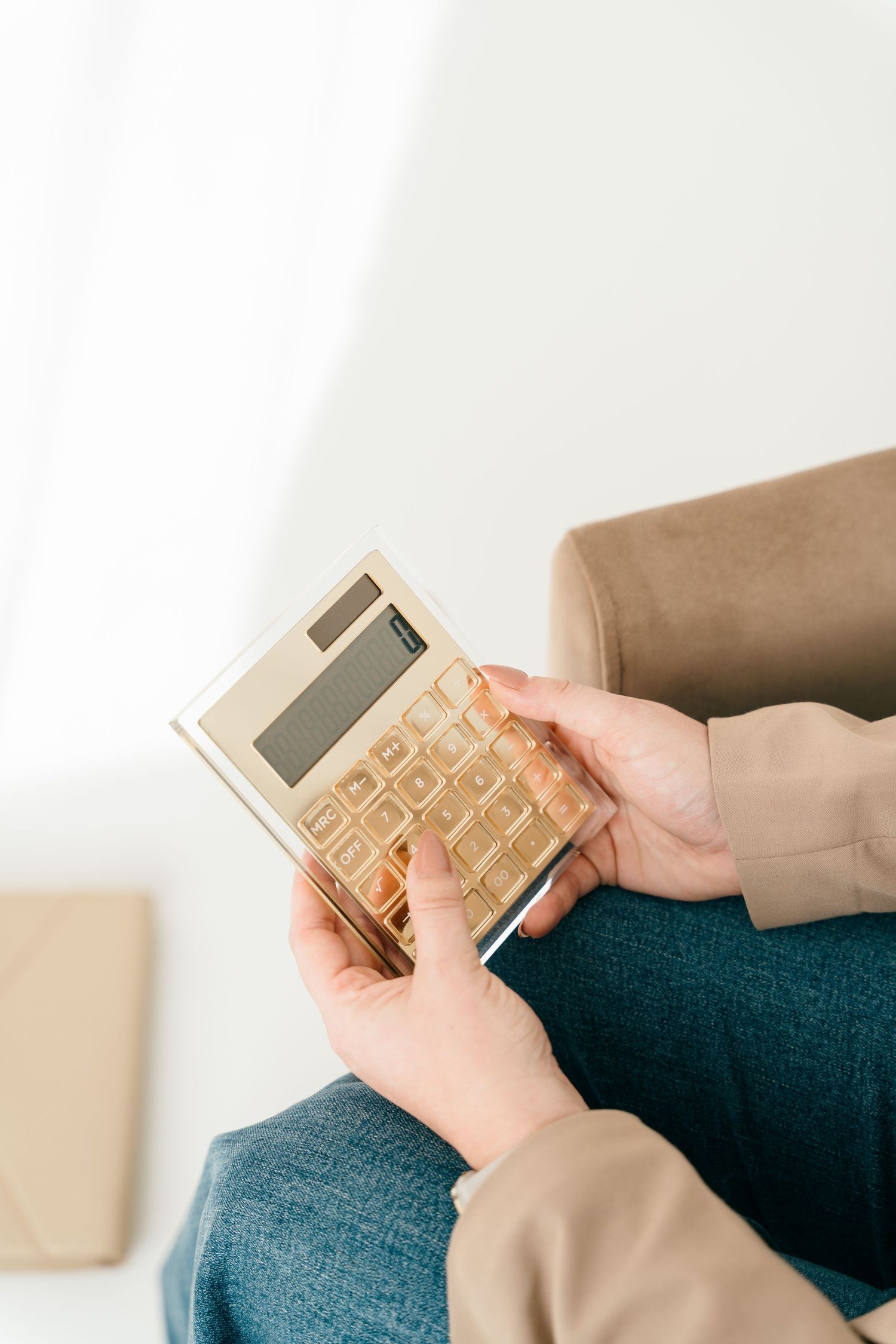 Hands holding gold calculator against white background.