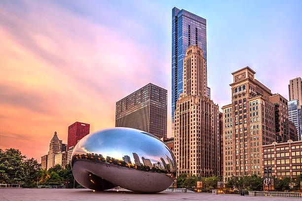 Cloud Gate sculpture reflects Chicago skyline against colorful sunset sky at Millennium Park.