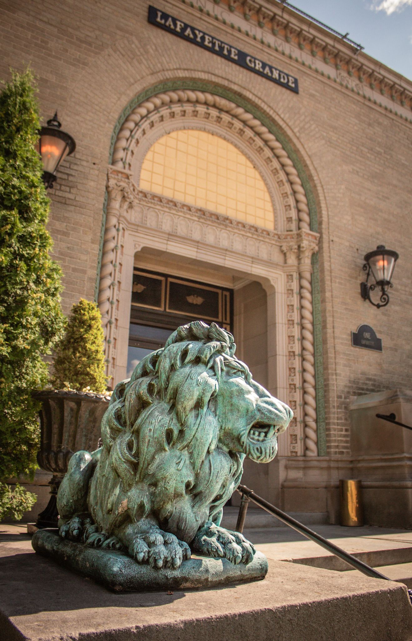 Large bronze lion statue guards entrance of historic Lafayette Building.