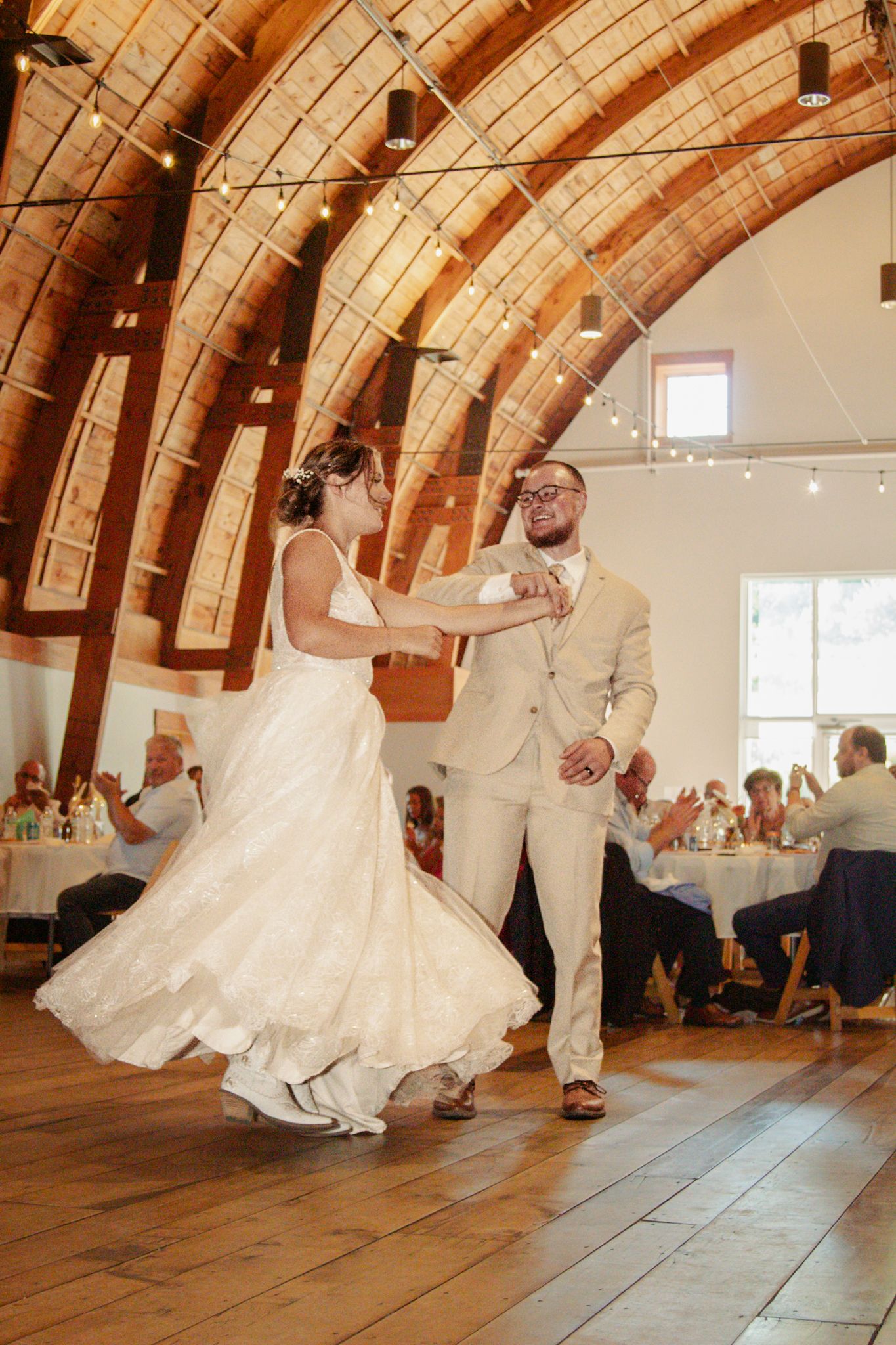 A wedding dance in a rustic wooden hall with vaulted ceiling and warm lighting at The Cathedral Barn in Traverse City, Michigan.