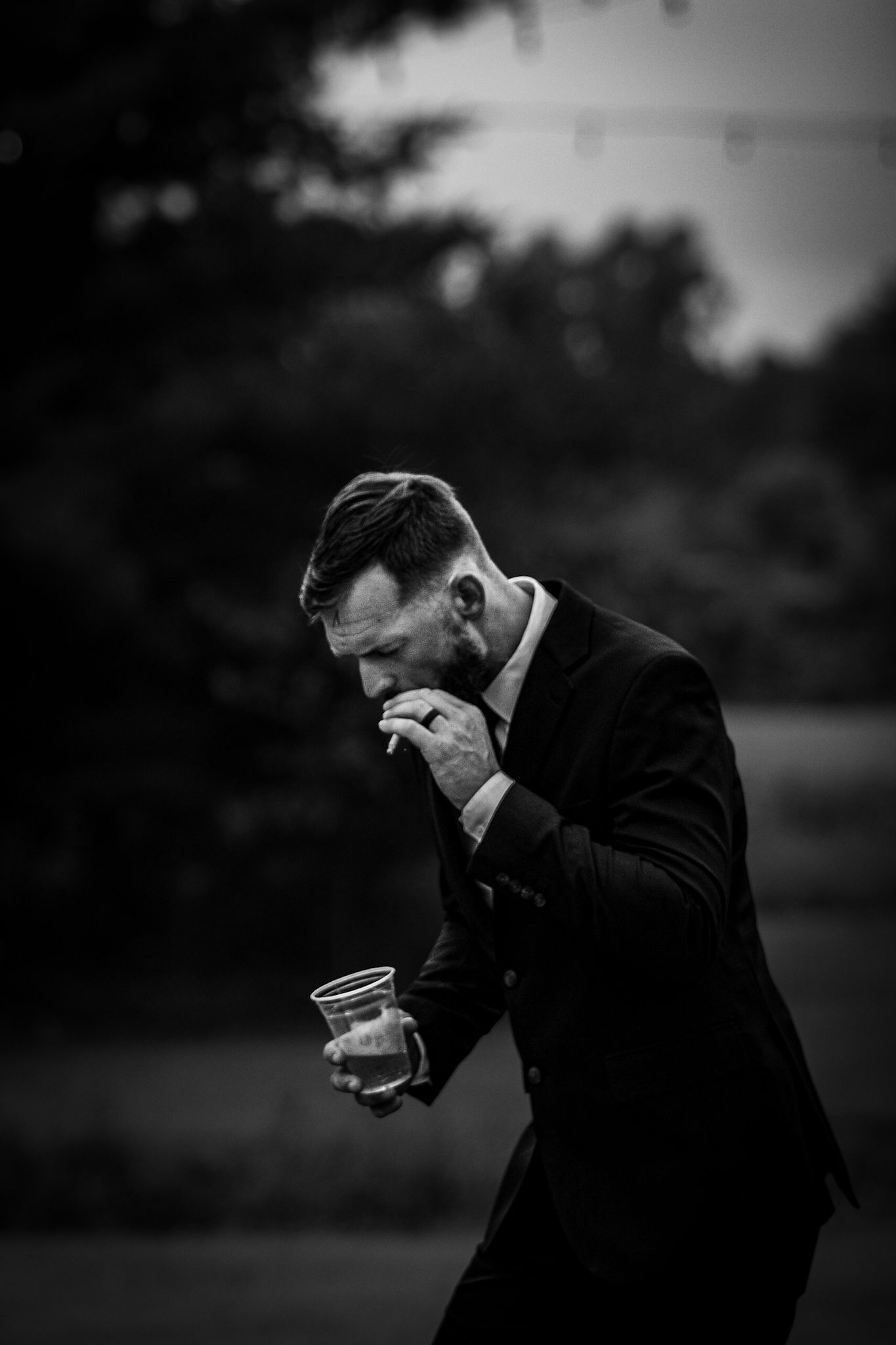 A moody photograph of a groom smoking a cigarette