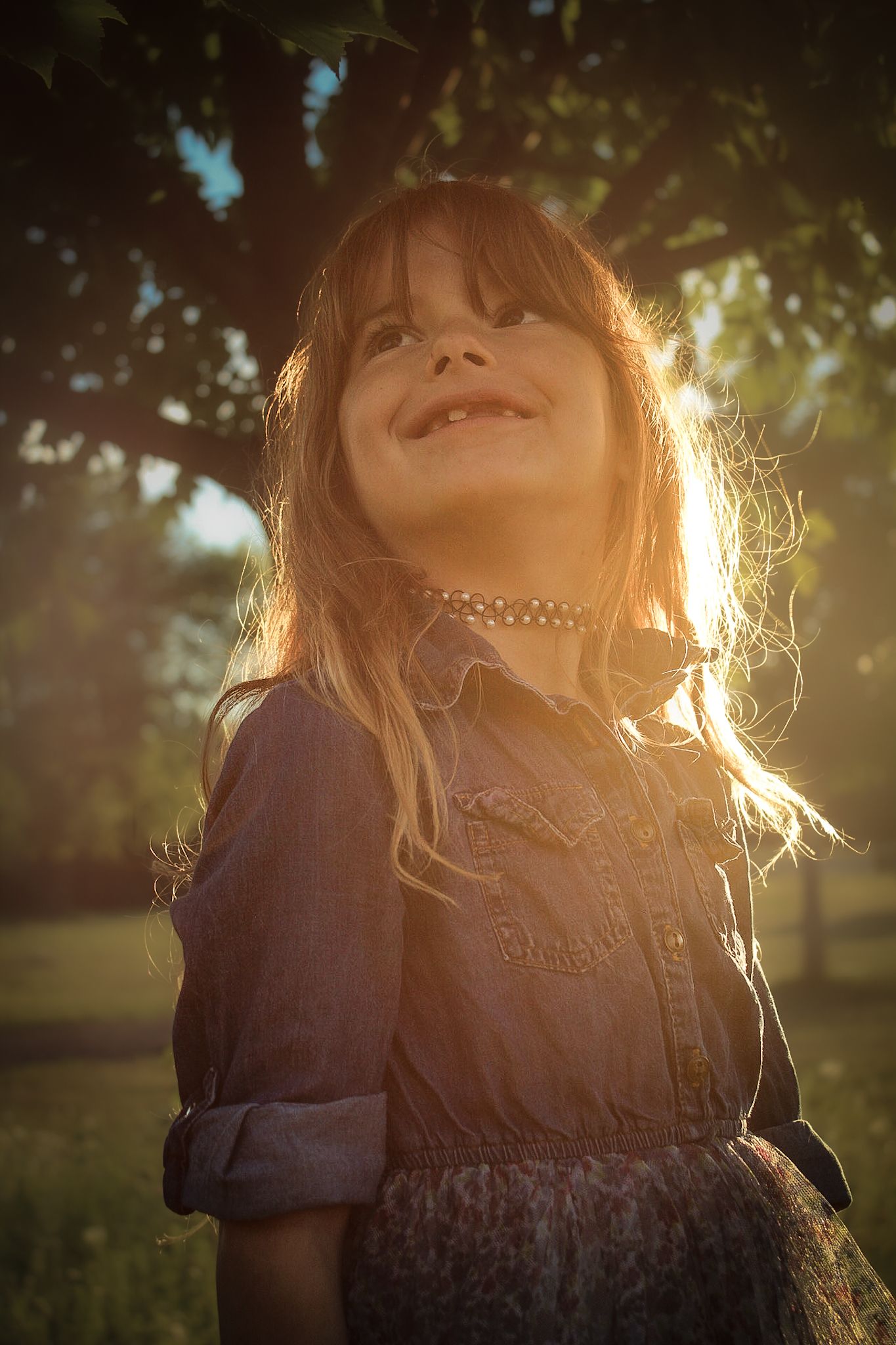Sunset portrait showing joyful expression with backlit hair and denim jacket.