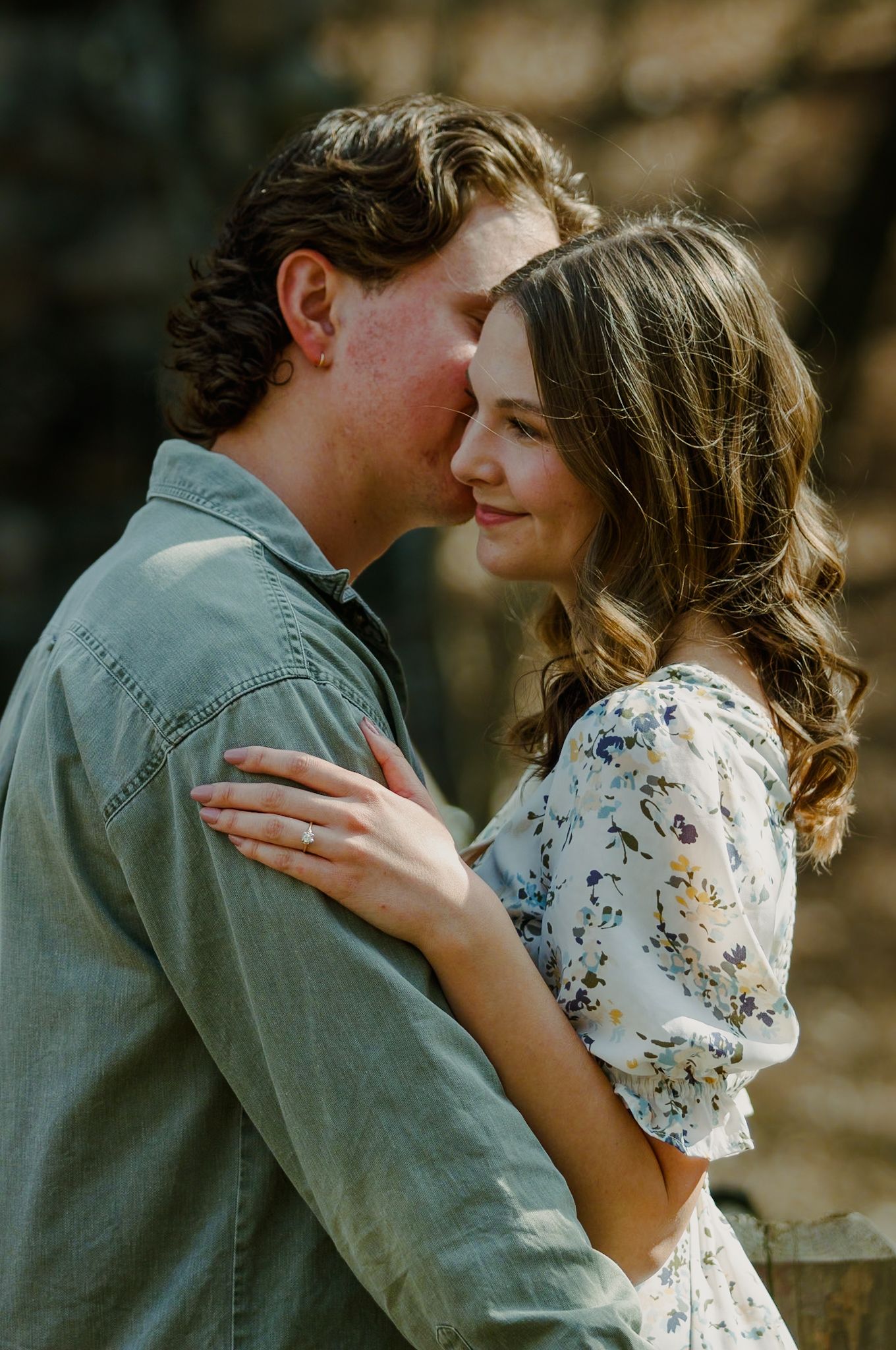 A romantic engagement photo of a couple in soft sunlight.