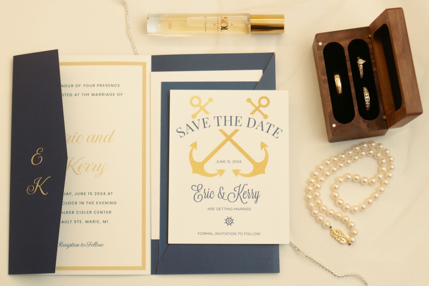 Wedding stationery featuring navy and gold save-the-date cards with pearl accessories.