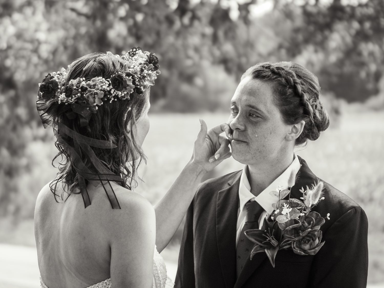 An intimate black and white wedding moment between two people wearing floral crowns.