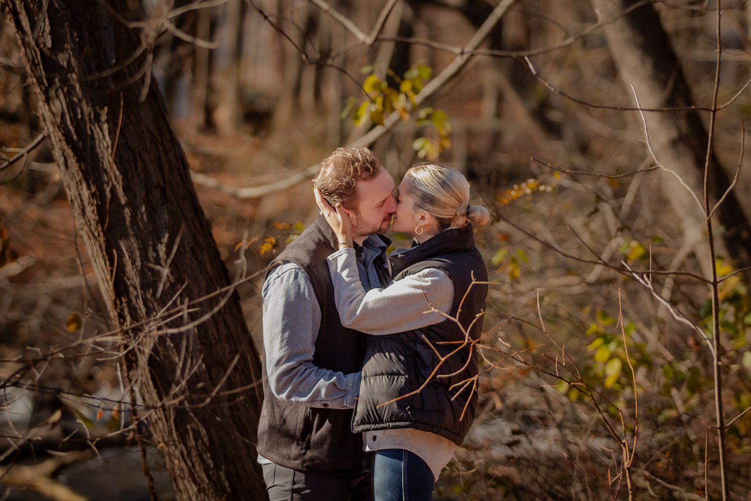 Engaged couple sharing a kiss in front of a river