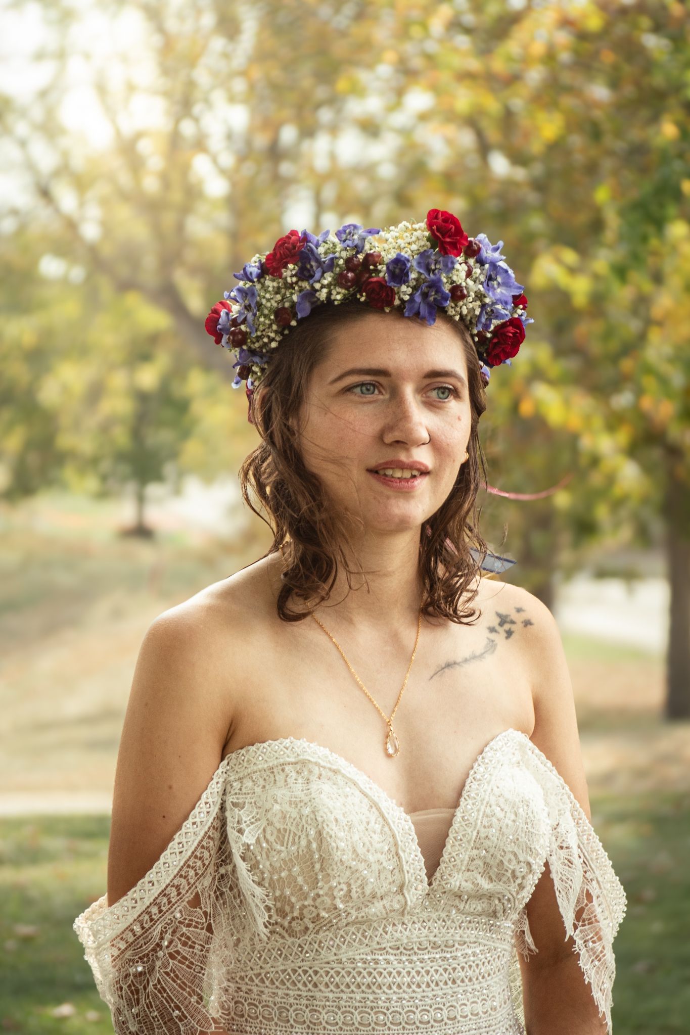 Bride wearing a bohemian lace dress and floral crown poses in golden autumn sunlight.