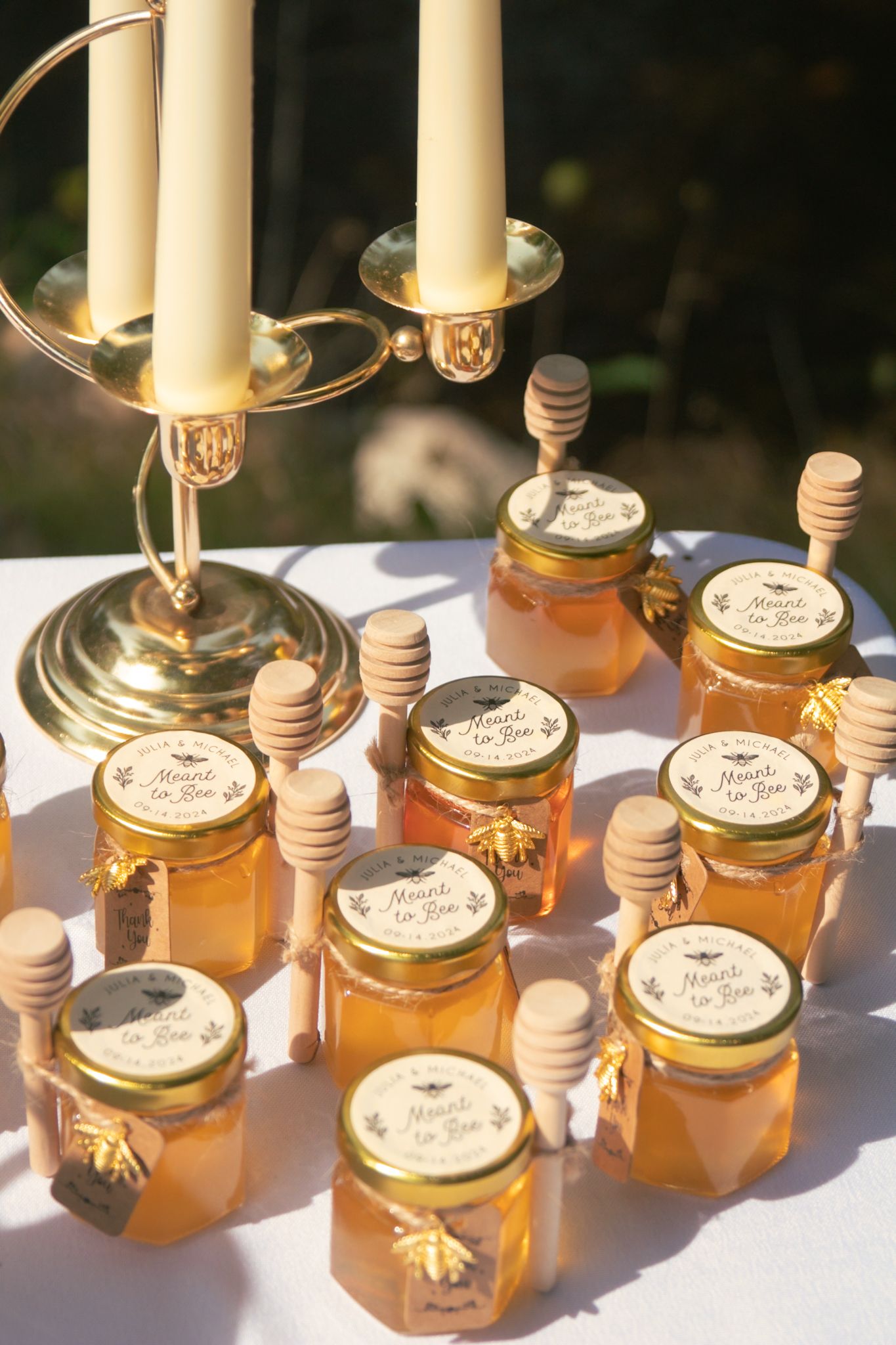 Honey wedding favors with wooden dippers displayed on table with elegant candelabra.