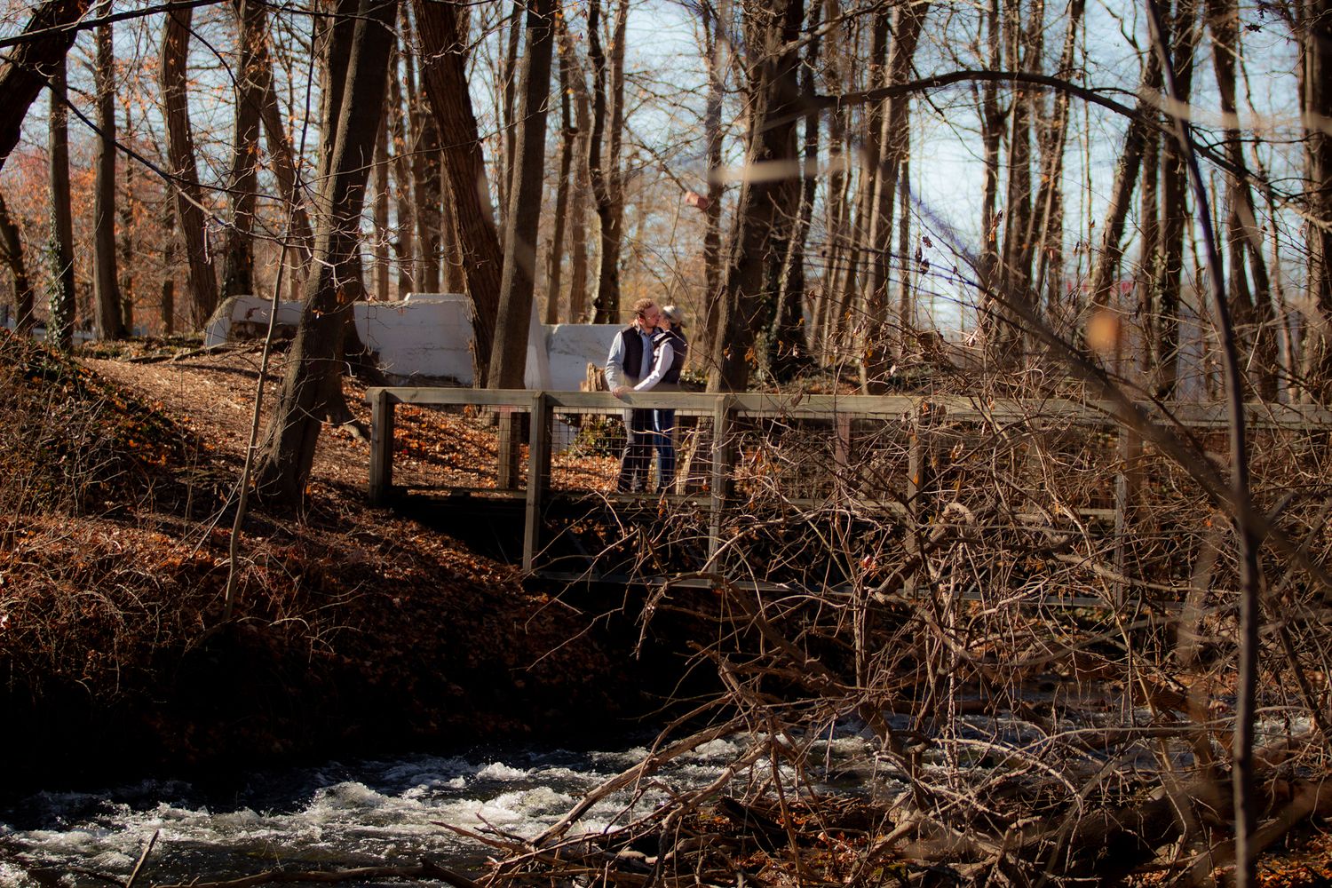 Engaged couple sharing a kiss standing on abridge over a river