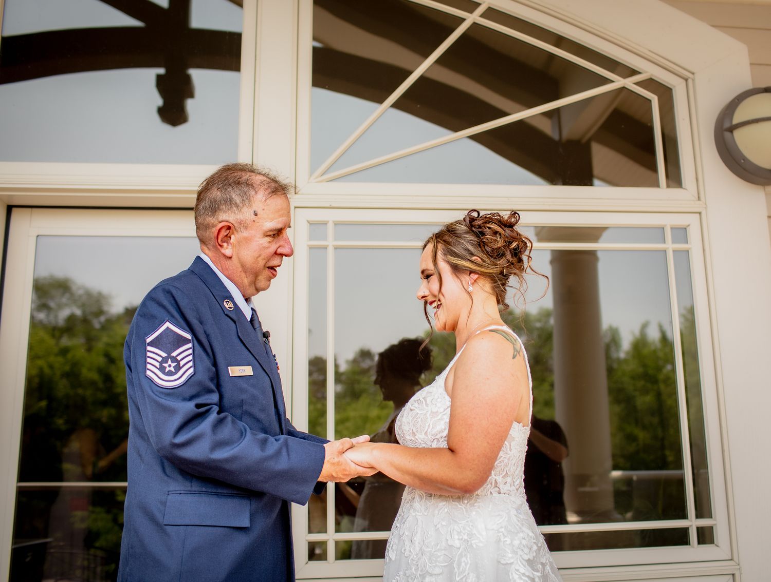 An emotional father-daughter first look wedding moment in front of a white doorway at Riverwalk Place venue in Gladwin Michigan.