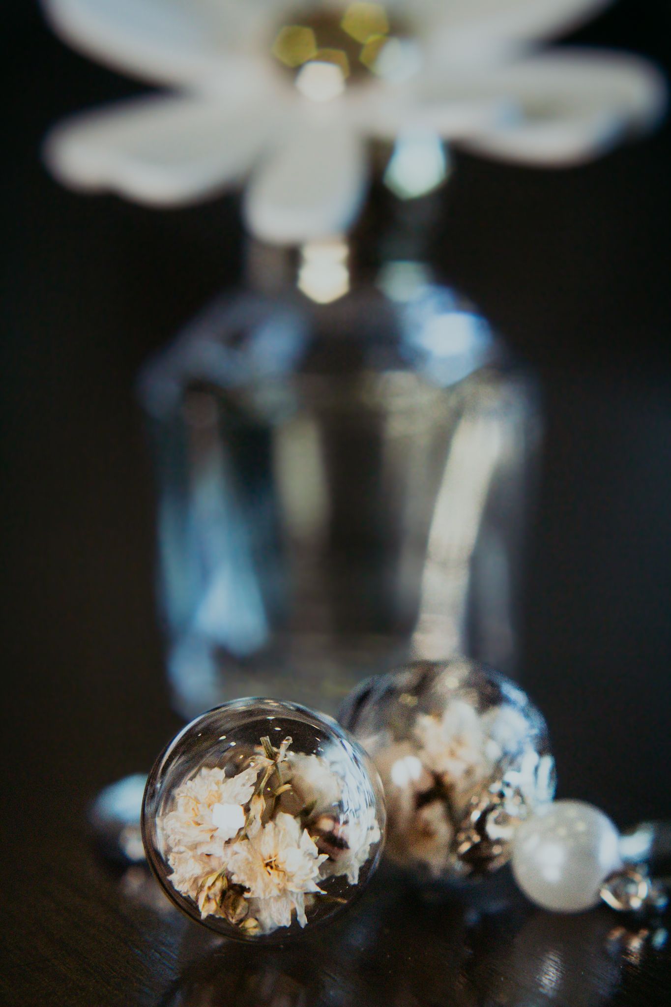 Close-up of delicate glass globe jewelry with dried flowers inside.