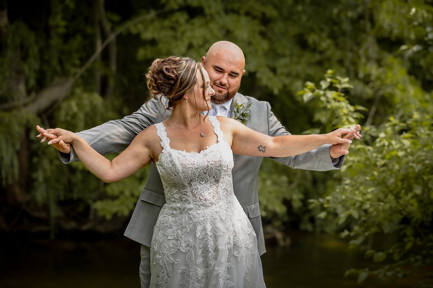 Newlyweds dance joyfully together in a lush green garden setting during their outdoor wedding celebration.