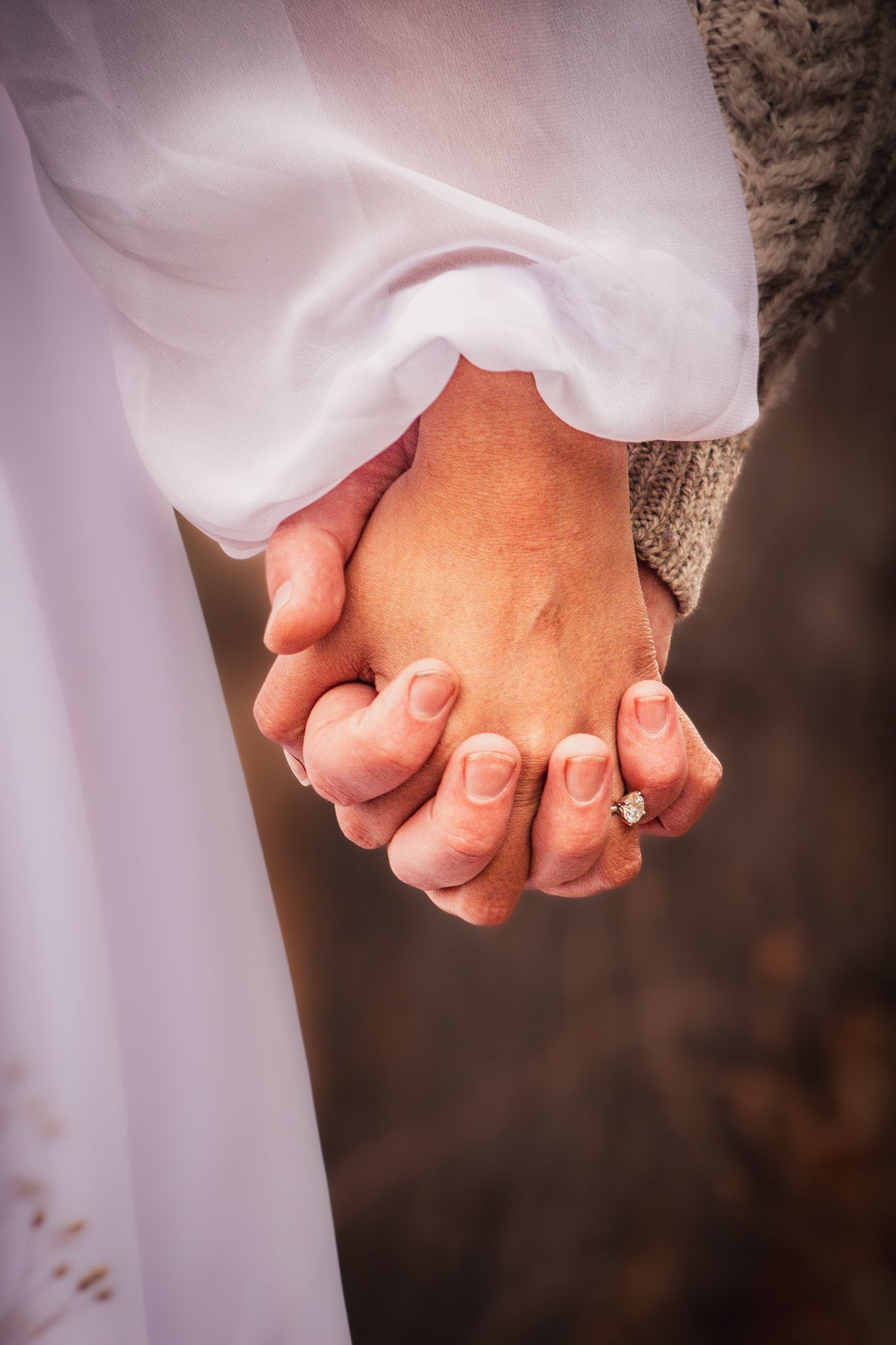 An engaged couple holding hands showcasing a stunning round cut engagement ring
